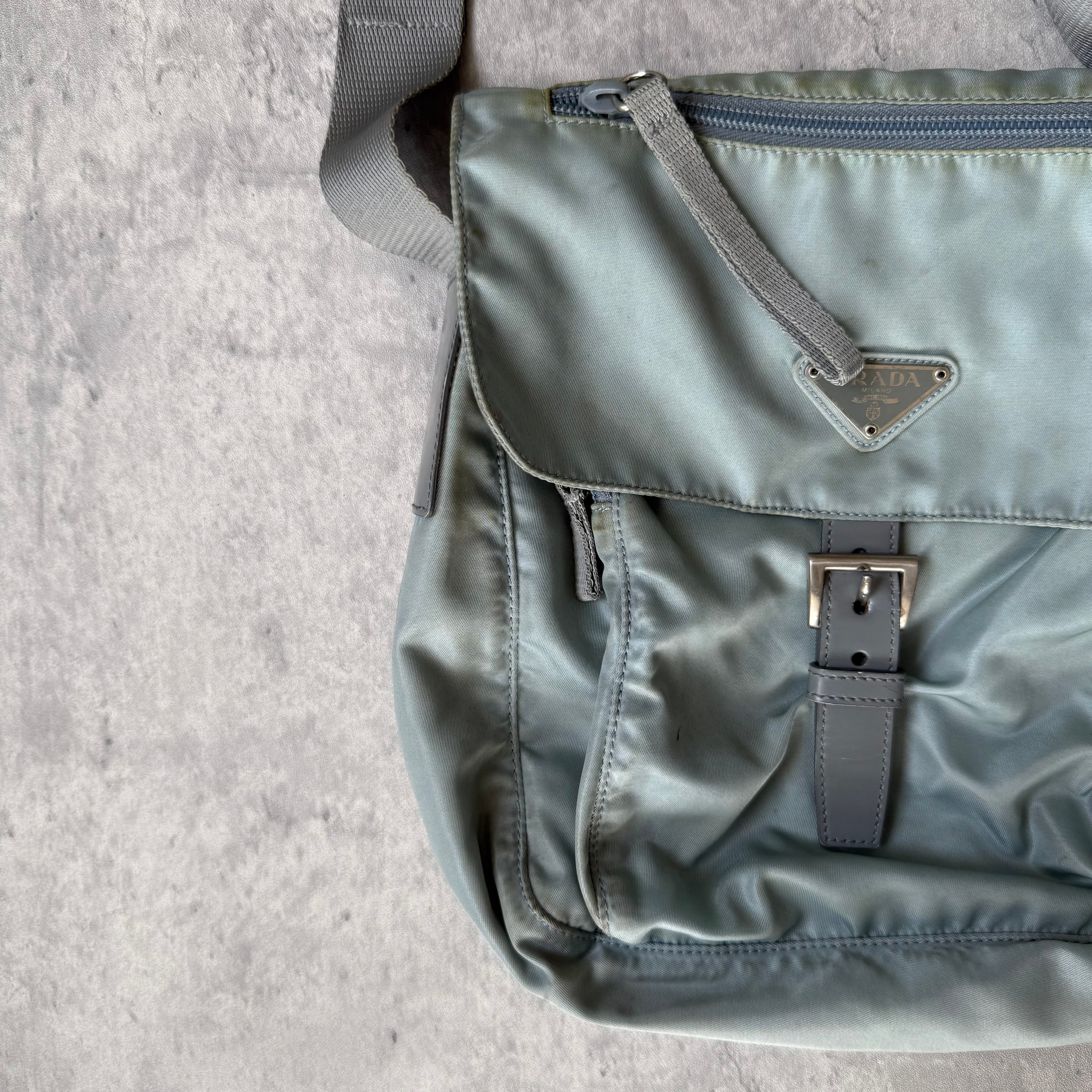Prada Nylon Front Buckle Shoulder Bag in light blue with grey strap, zip and buckle compartments, and Prada logo plaque.