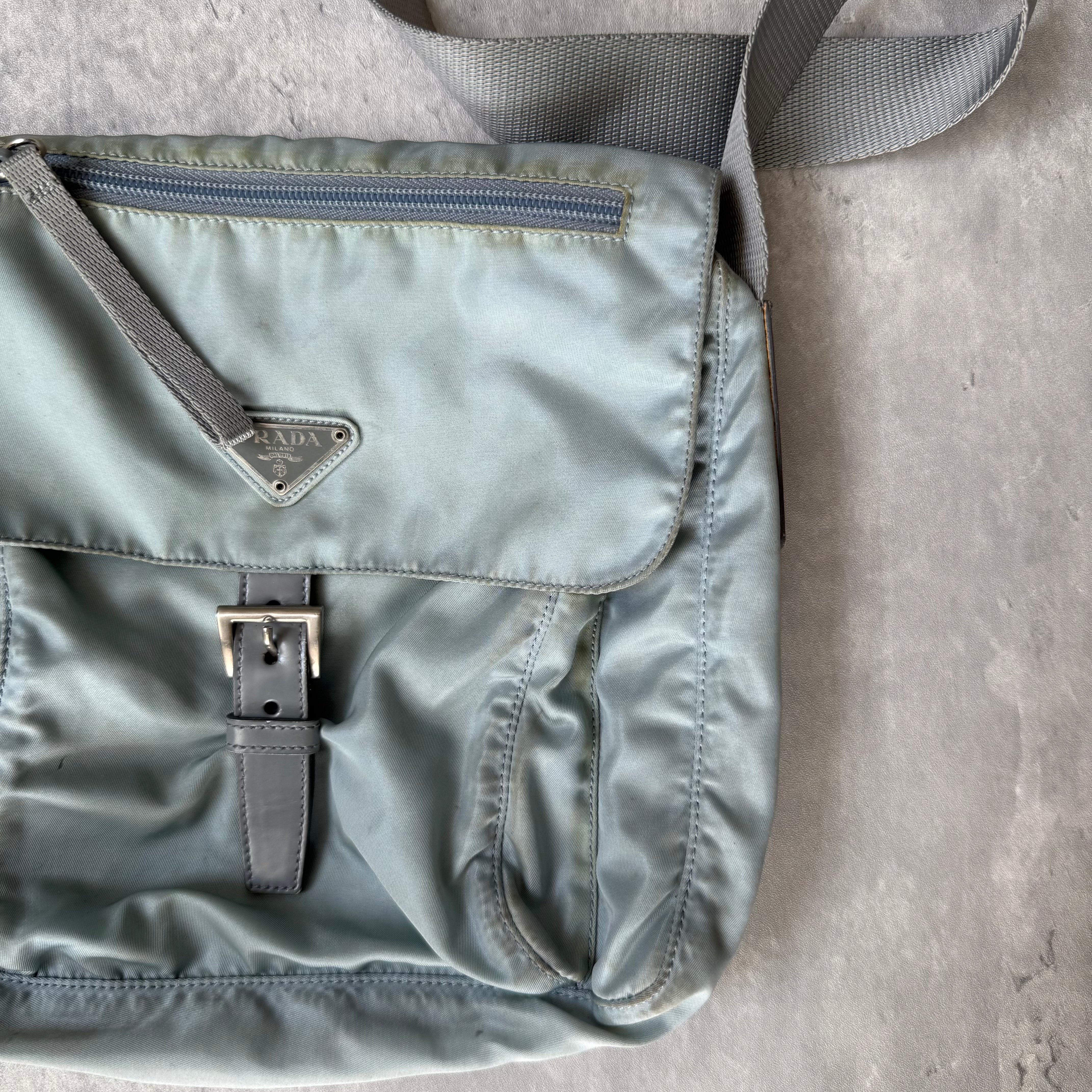 Prada Nylon Front Buckle Shoulder Bag in light blue with grey strap, zip and buckle compartments, and Prada logo plaque.