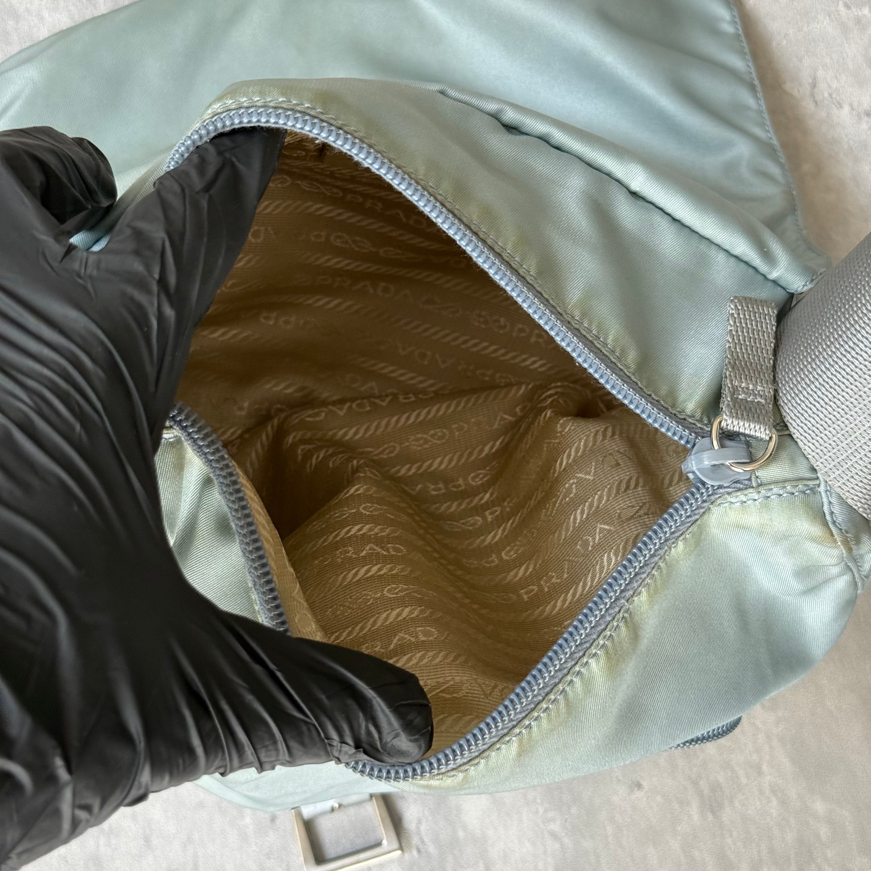 Prada Nylon Front Buckle Shoulder Bag in light blue with grey strap, zip and buckle compartments, and Prada logo plaque.