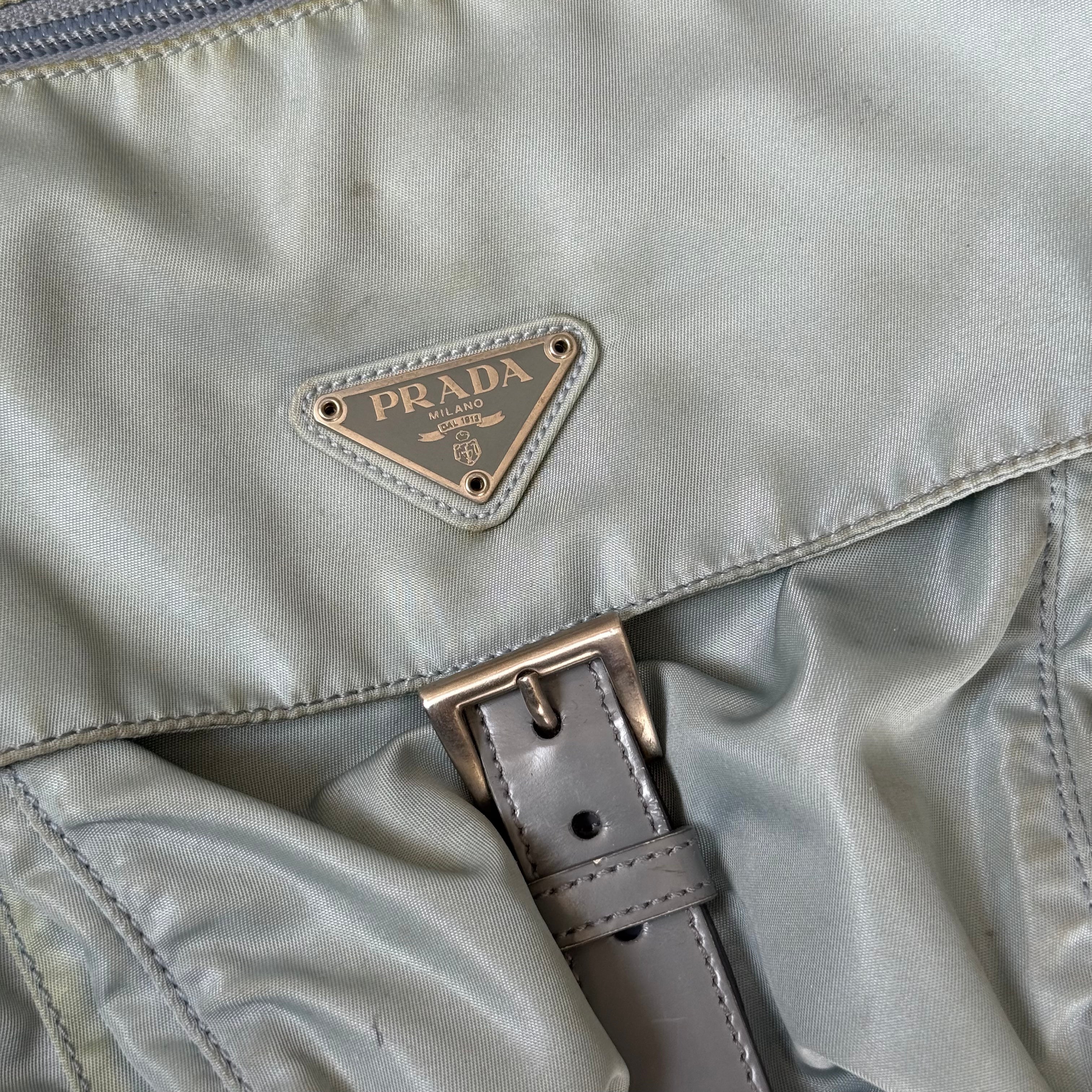 Prada Nylon Front Buckle Shoulder Bag in light blue with grey strap, zip and buckle compartments, and Prada logo plaque.