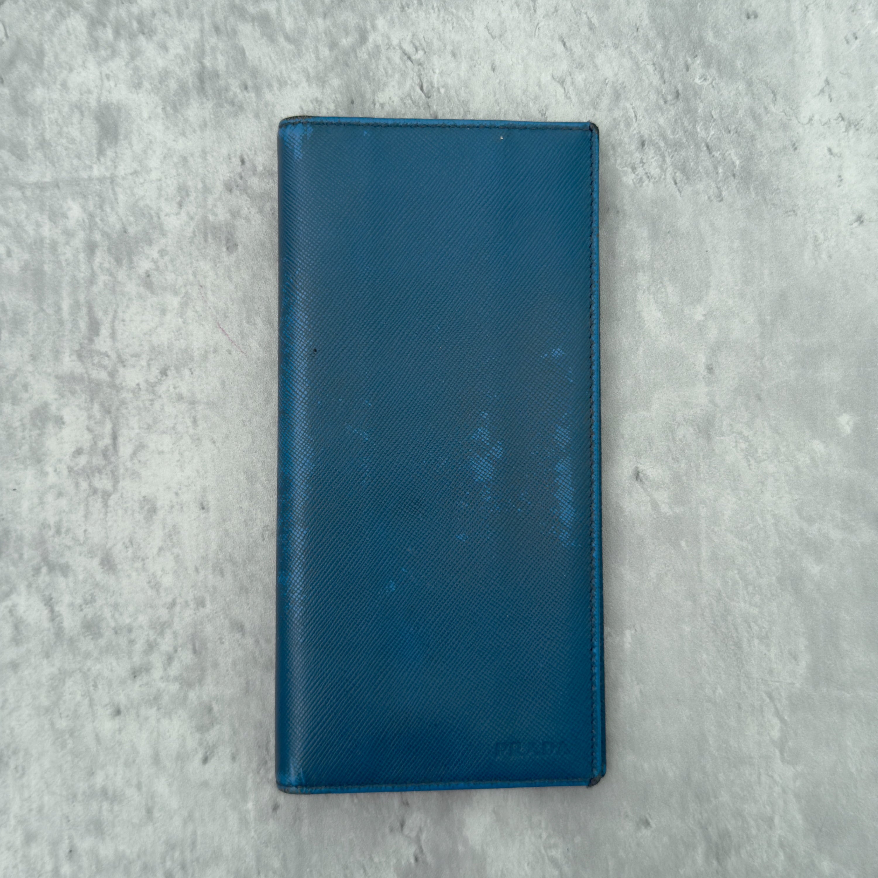 Prada Saffiano Baby Blue Long Wallet in Saffiano leather, featuring an embossed Prada logo, multiple card slots, and a zippered coin compartment.