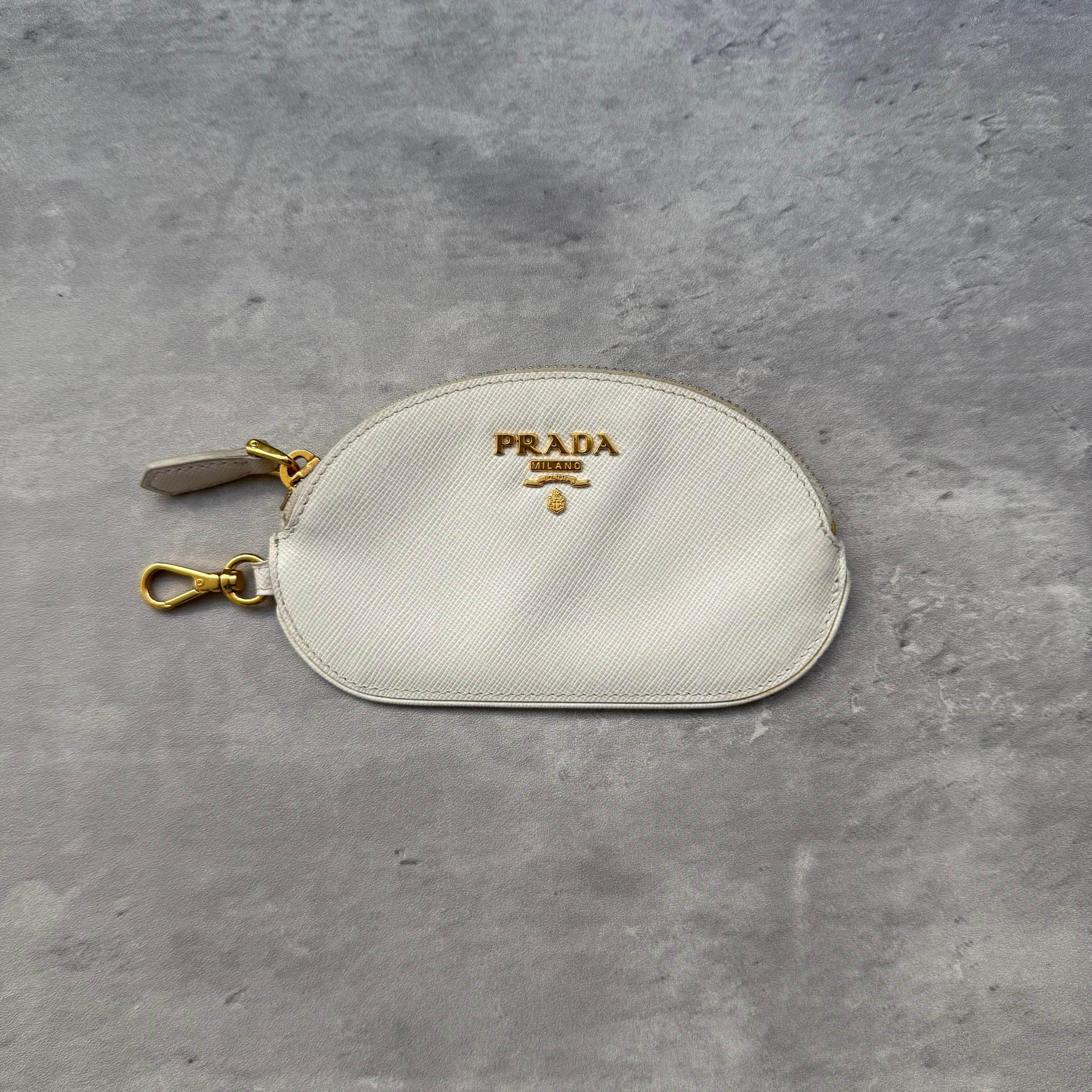 Prada Saffiano Coin Purse in white leather with gold-tone logo and clasp, featuring zip closure and monogram-lined interior.
