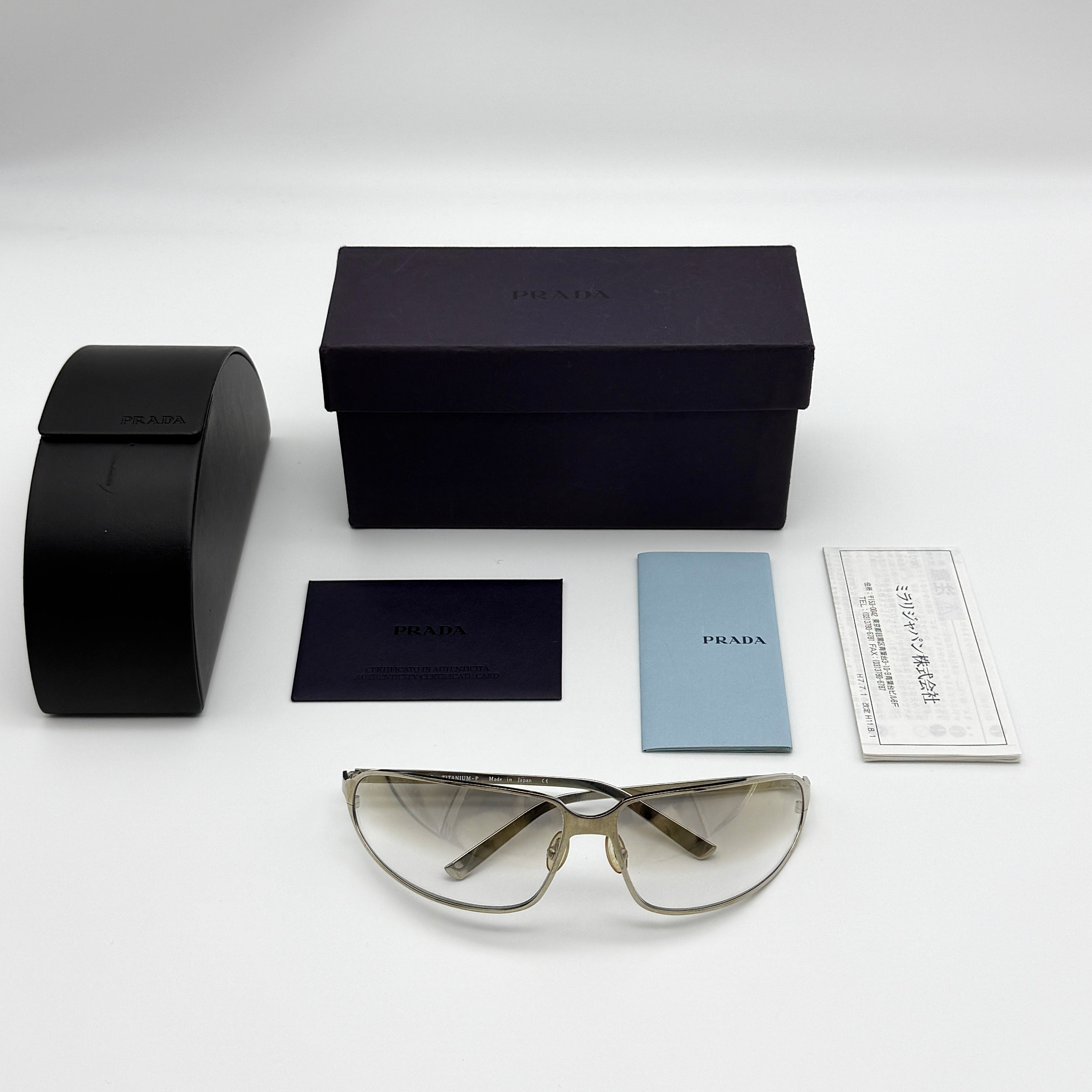 Prada Transparent Silver Vintage Sunglasses with a sleek titanium frame and clear gradient lenses, featuring an engraved Prada logo on the temples.