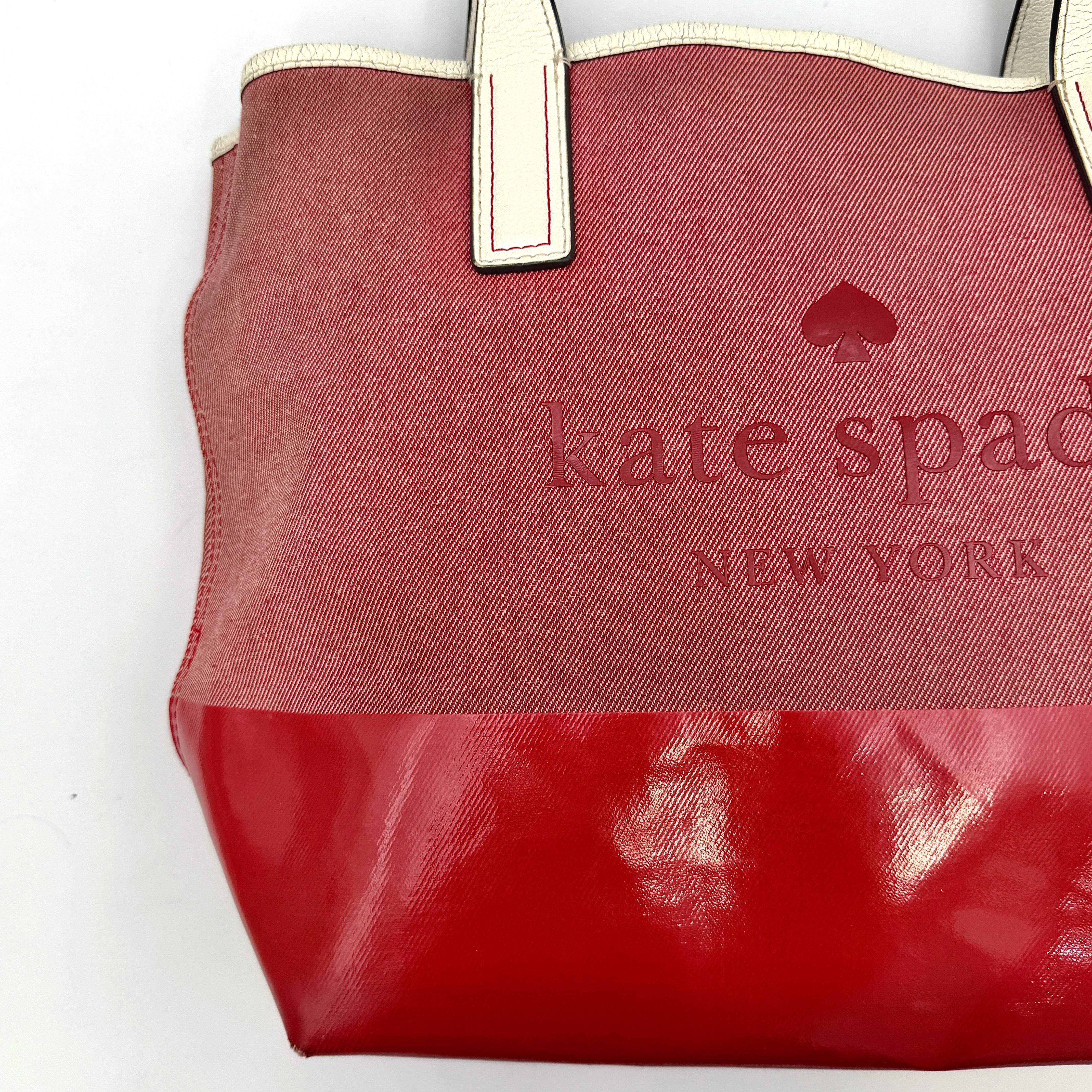 Kate Spade Ash Street Logo Tote in red canvas with glossy red leather base and ivory handles, shown against a white background.