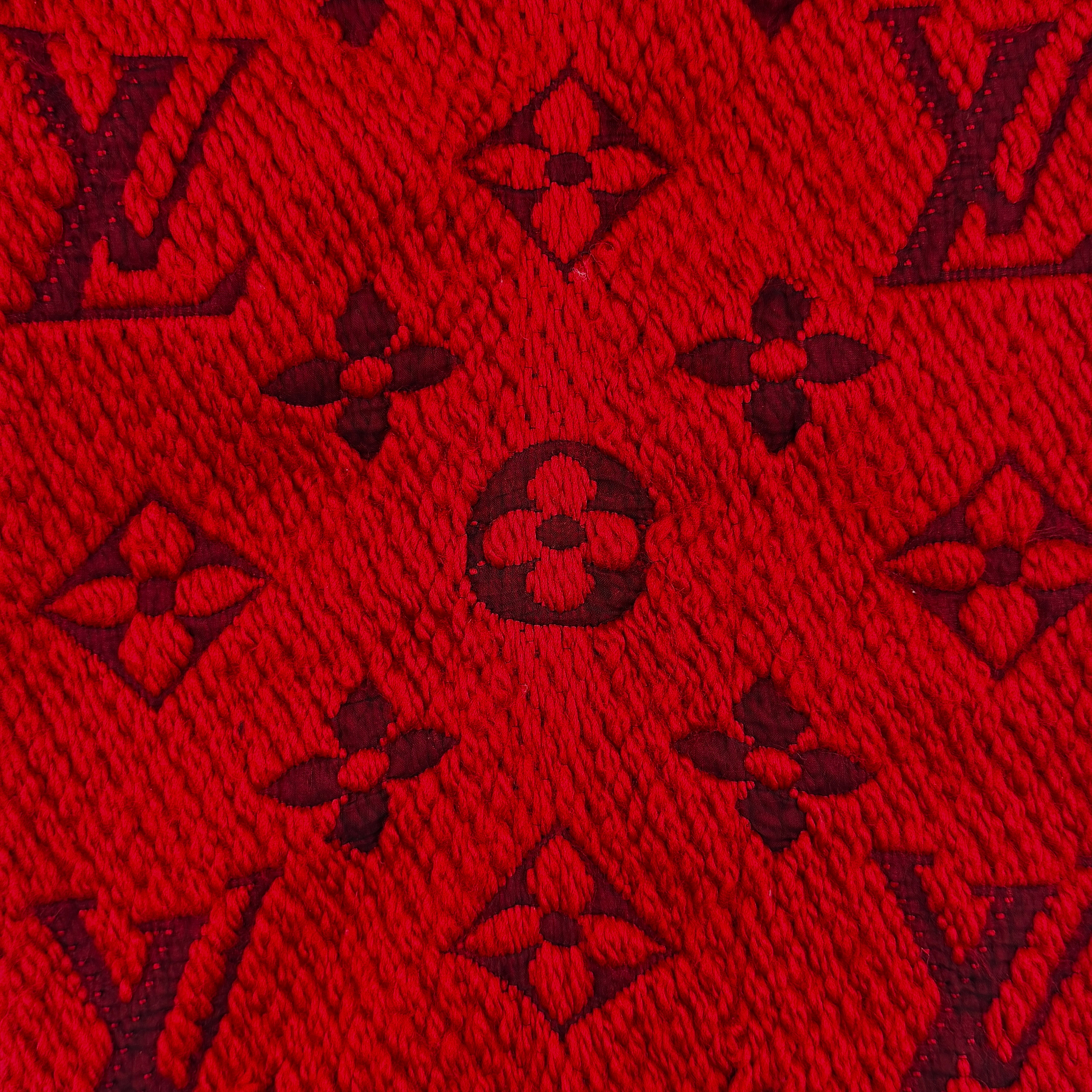 A luxurious Louis Vuitton Monogram Echarpe wool scarf in vibrant red, distinguished by its chunky texture, signature monogram pattern, and playful fringe edging.