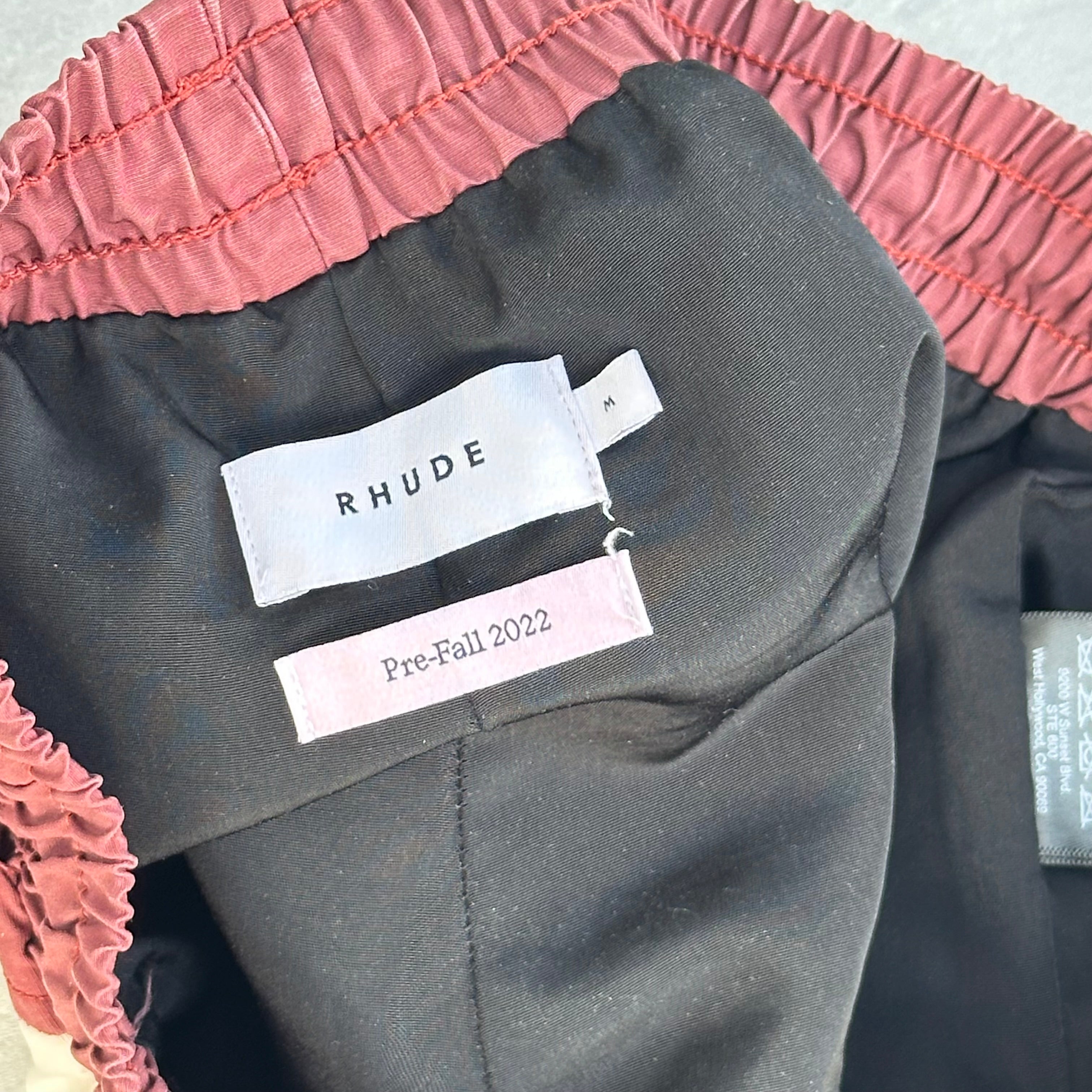 Rhude Panel Logo Shorts Maroon/White/Multi FW22, featuring championship print and moon graphic, with yellow drawstring and bold panel design.