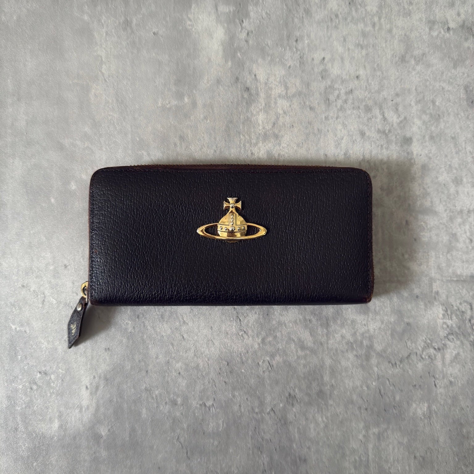 Vivienne Westwood Seditionaries Wallet, black leather, featuring the iconic gold-tone Orb emblem and a zip-around closure, interior detailed with brand's signature pattern.