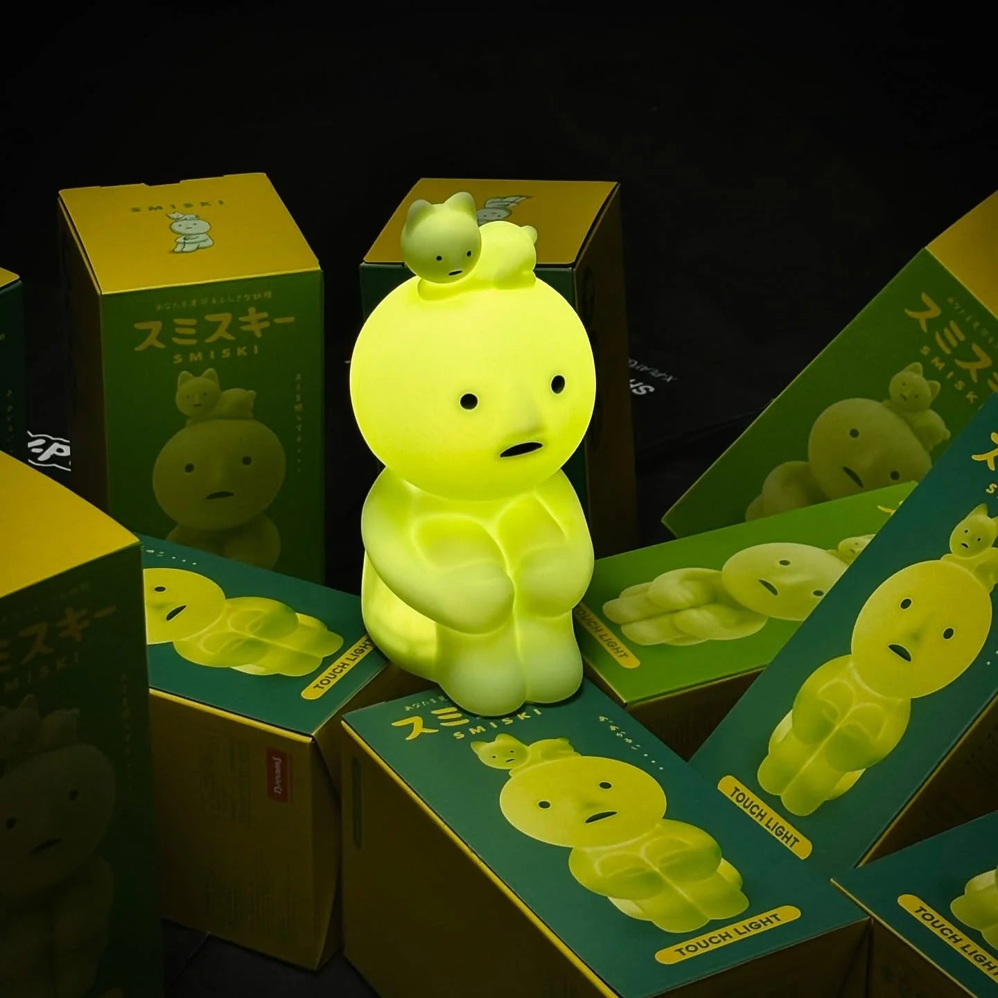Smiski Touch Light glowing softly on a desk, featuring a seated Smiski figure with a cat character on its head