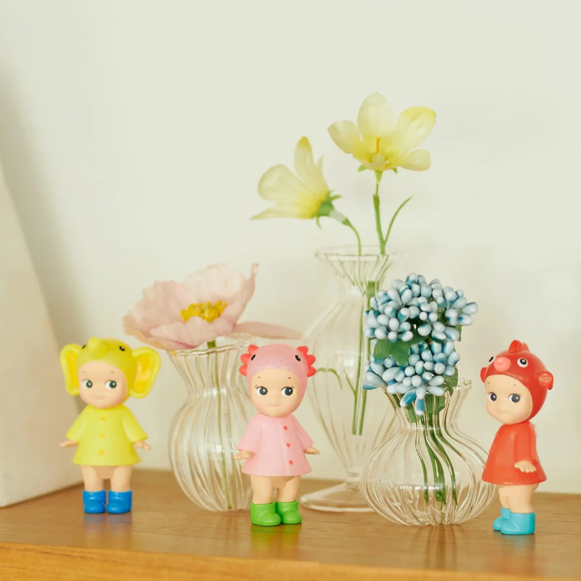 Sonny Angel I Love Rainy Day Series mini figures wearing colorful animal-themed raincoats and boots, displayed with flowers and soft background decor.
