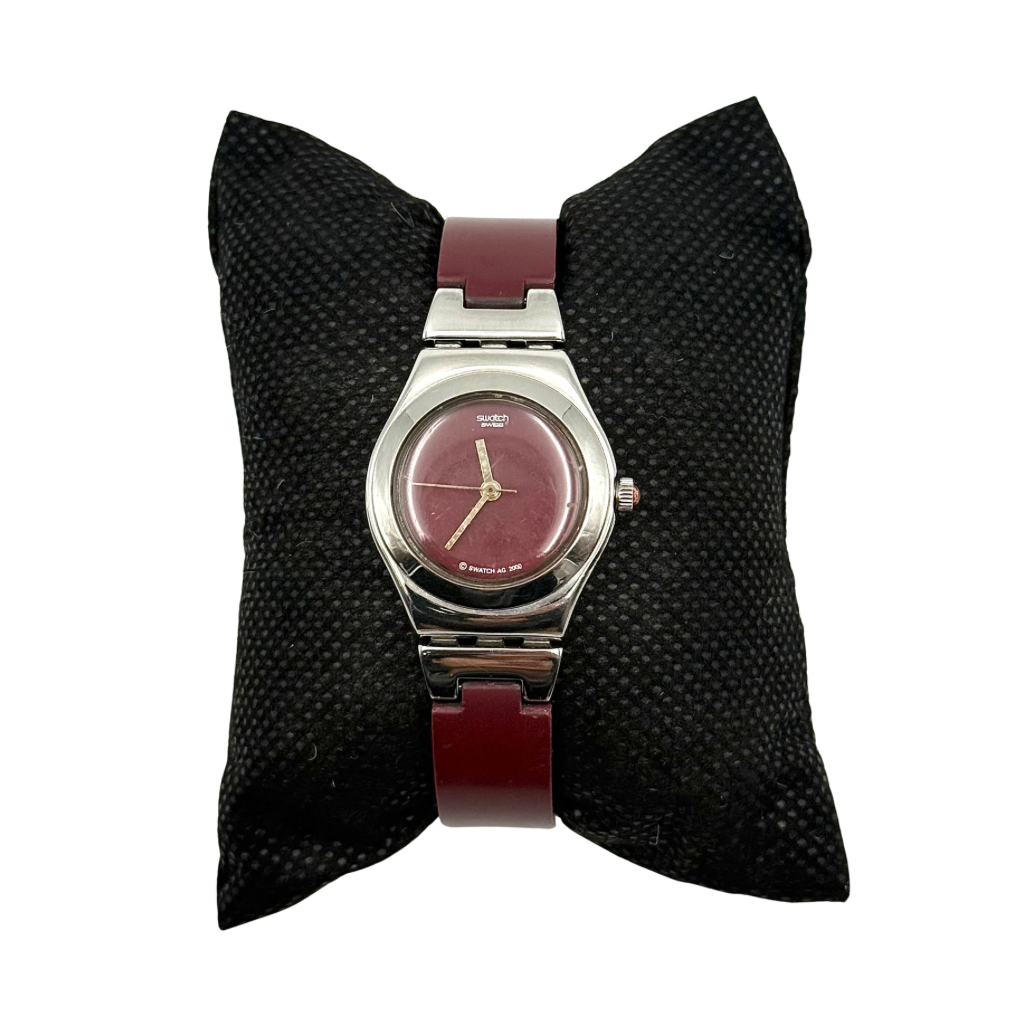 Swatch Irony Lady Angels Call watch in burgundy and silver, presented on a black cushion.