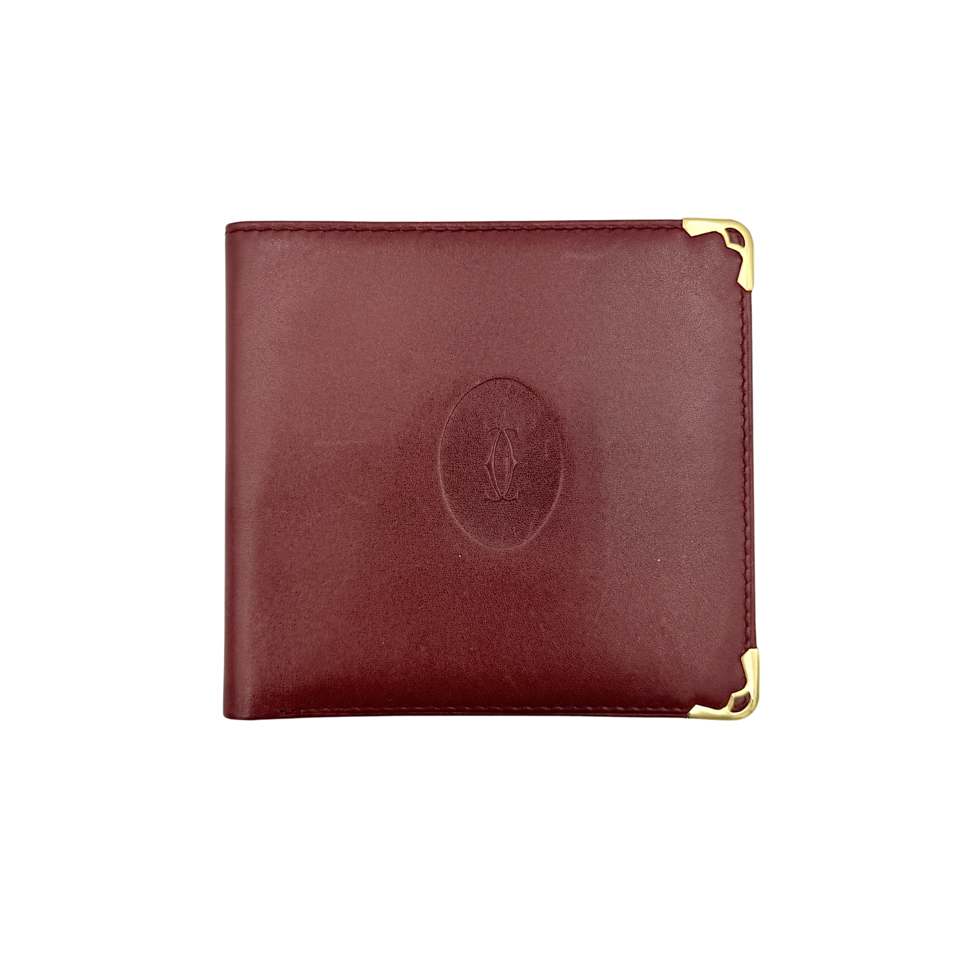 Cartier Must de Cartier leather wallet in rich burgundy with gold-tone corner accents and an embossed logo, photographed closed against a white background.