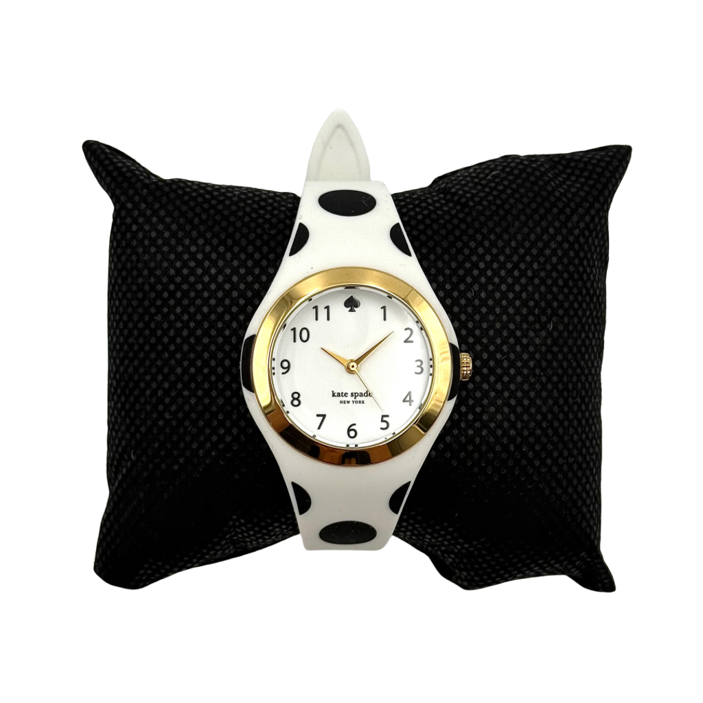 Kate Spade New York Rumsey 0838 silicone watch in white with black polka dots, gold-tone bezel, and white dial displayed on a cushion.