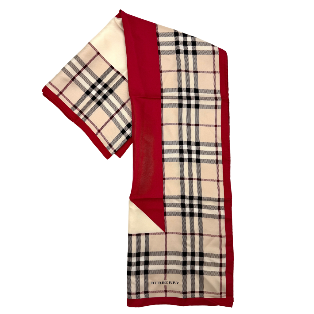 A Burberry silk scarf with beige check pattern, bold red borders, and ivory geometric panels, artfully arranged to showcase its contemporary elegance.