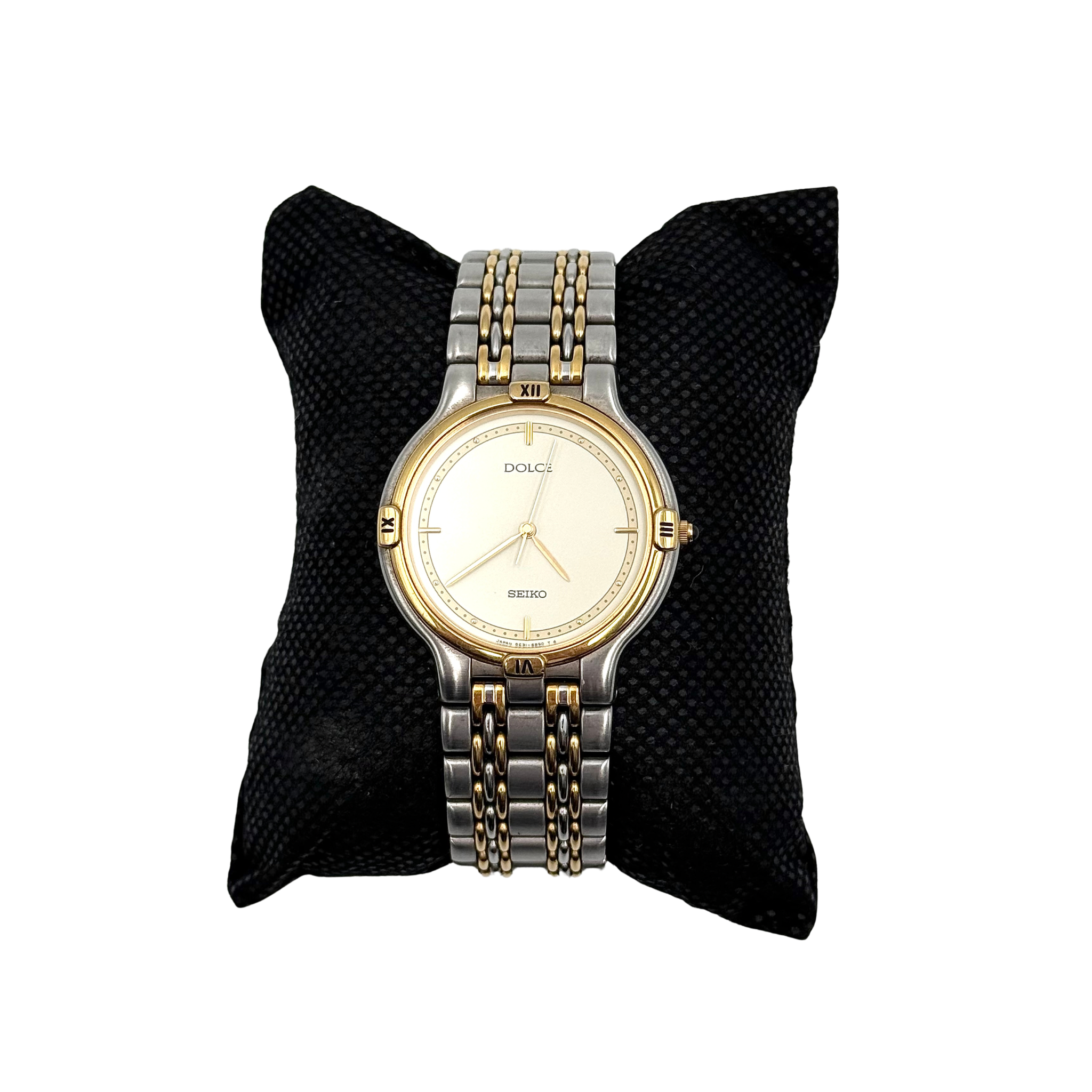 Seiko Dolce 5E31-6B90 watch in stainless steel with gold-tone accents and a cream dial, displayed on a black cushion.