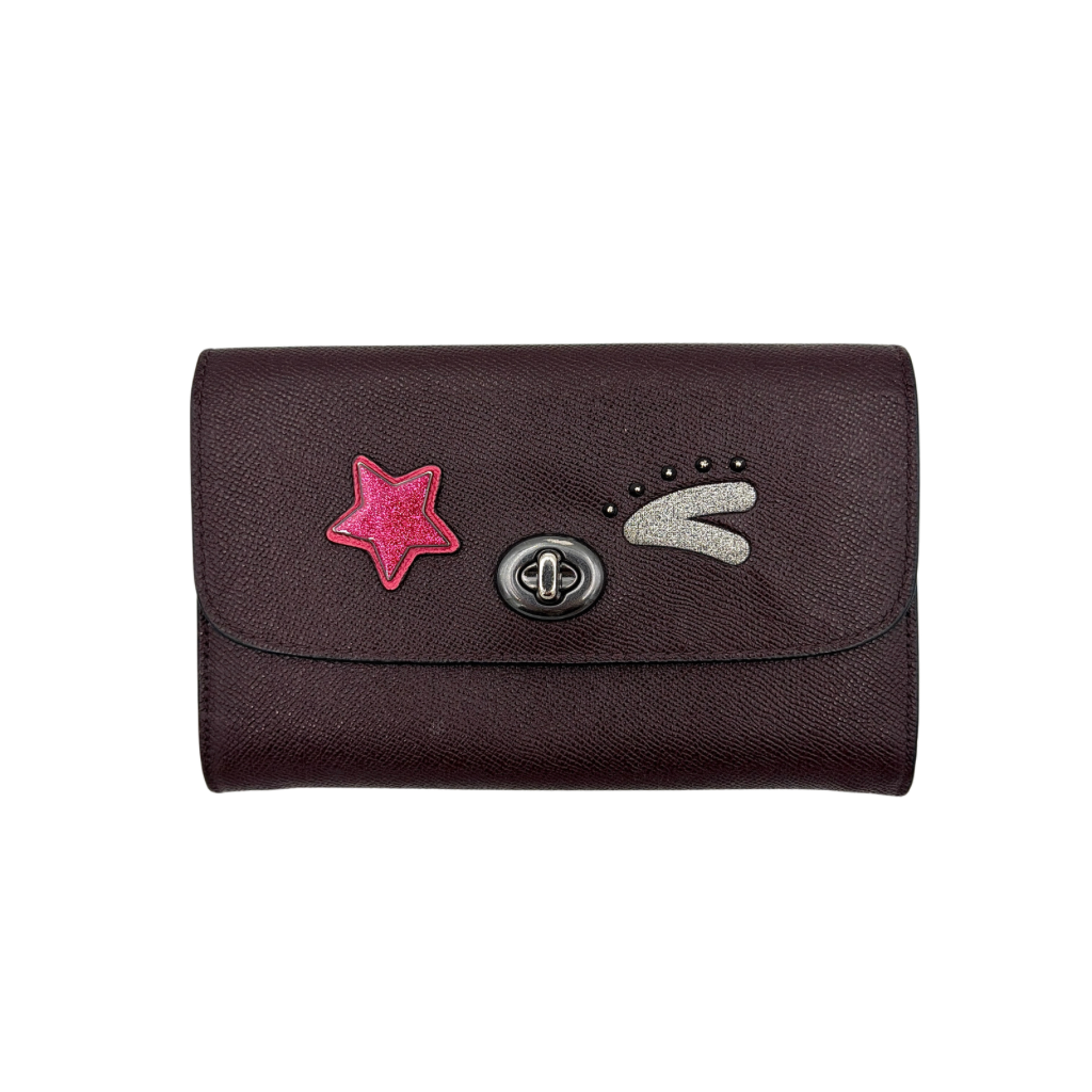 Coach Bear Turnlock Clutch in burgundy leather with playful pink and silver star details and signature gunmetal turnlock front closure.