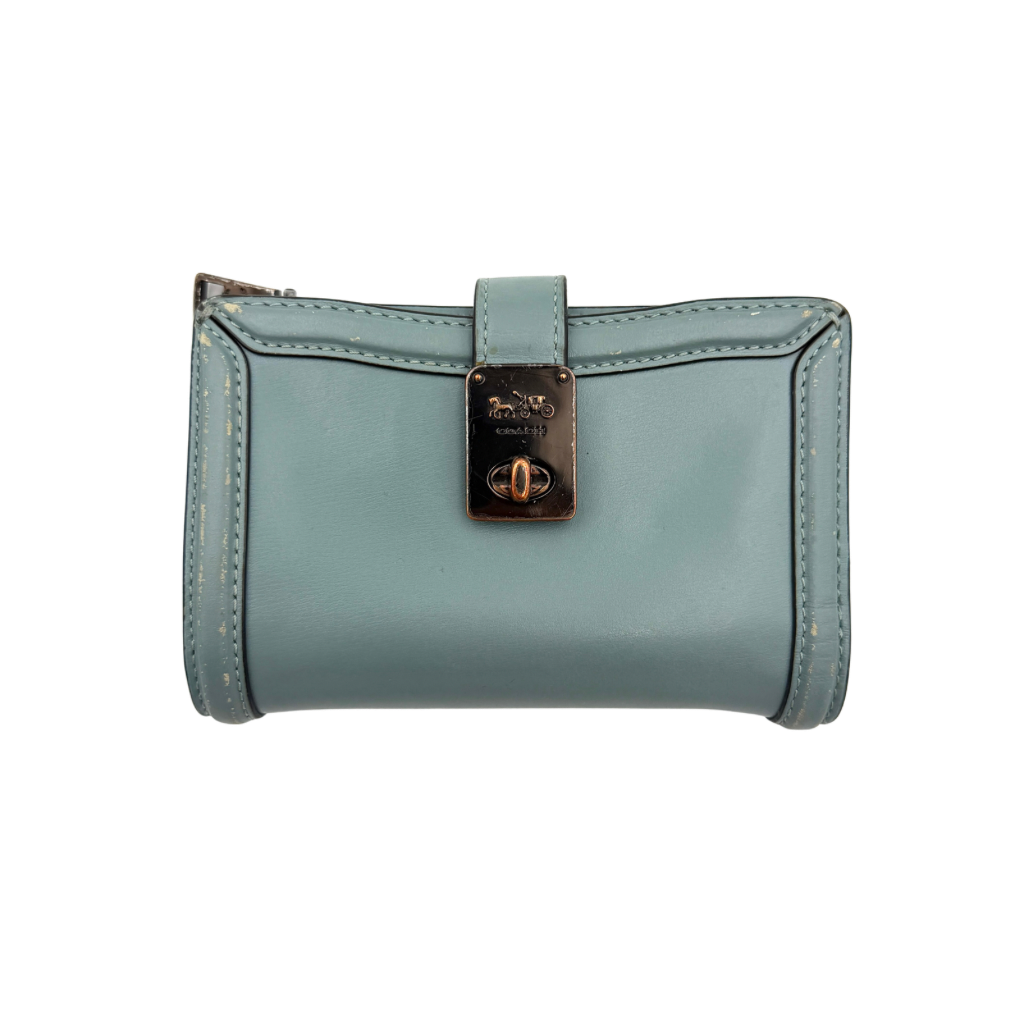 Coach Hutton Turnlock Wallet in light blue leather with signature gold turnlock clasp, showcased from the front.
