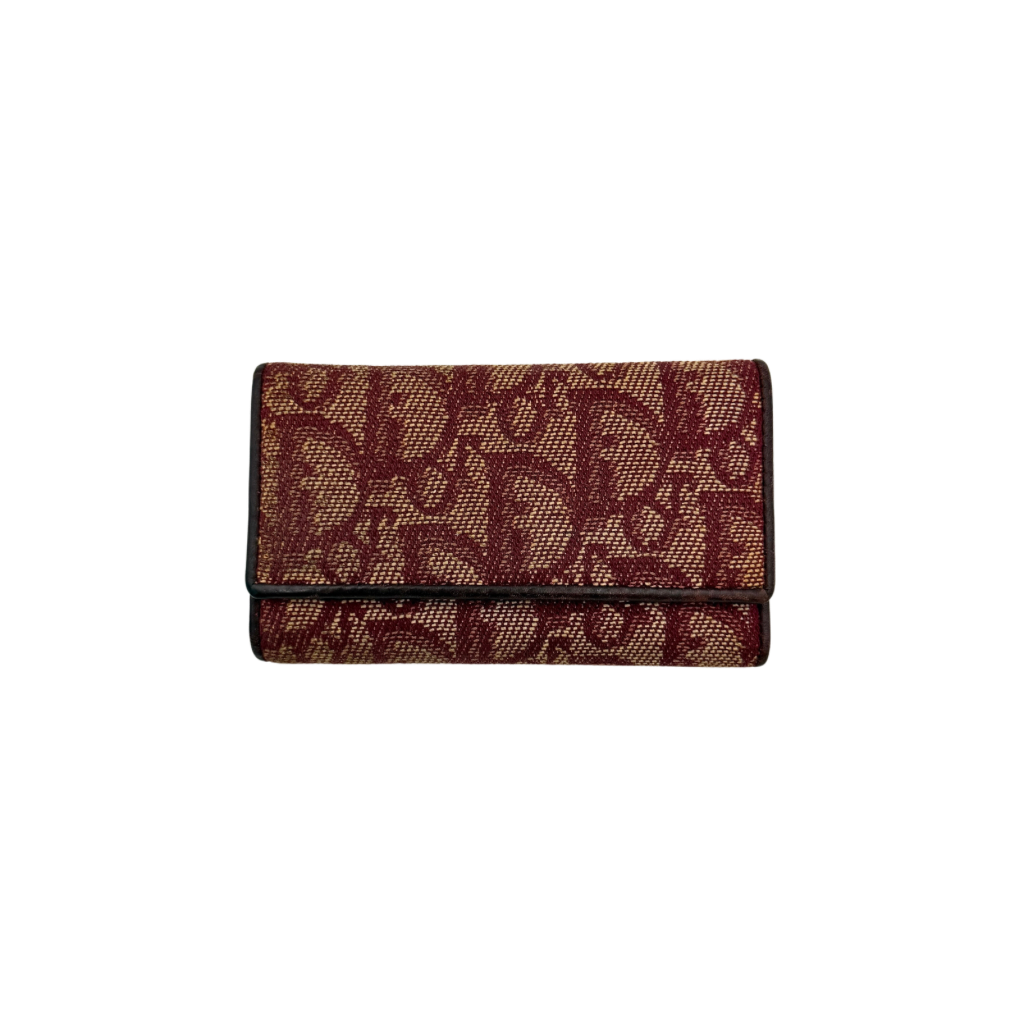 Dior Trotter Monogram key holder in red canvas with burgundy leather trim, photographed closed on a clean white background.