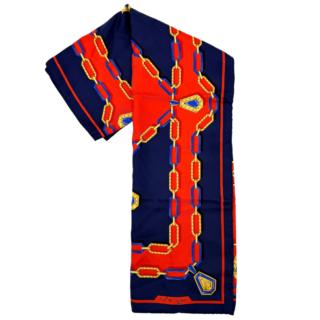 Cartier Must de Cartier silk scarf with striking navy, red, and gold chain motif and jewel accents, styled in a folded drape.