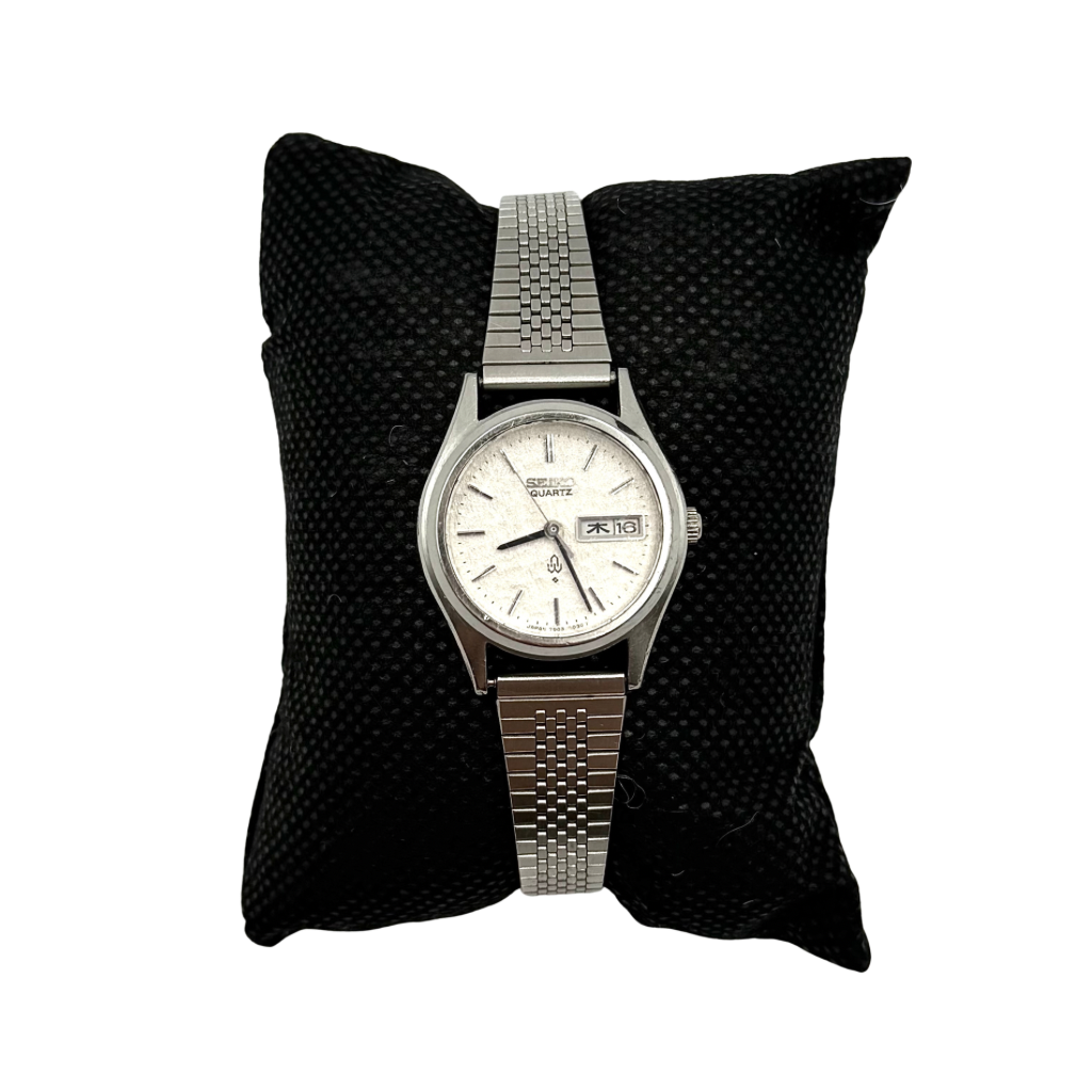 Seiko 7903-0030 Quartz stainless steel watch with a white textured dial and matching steel bracelet on a display pillow.
