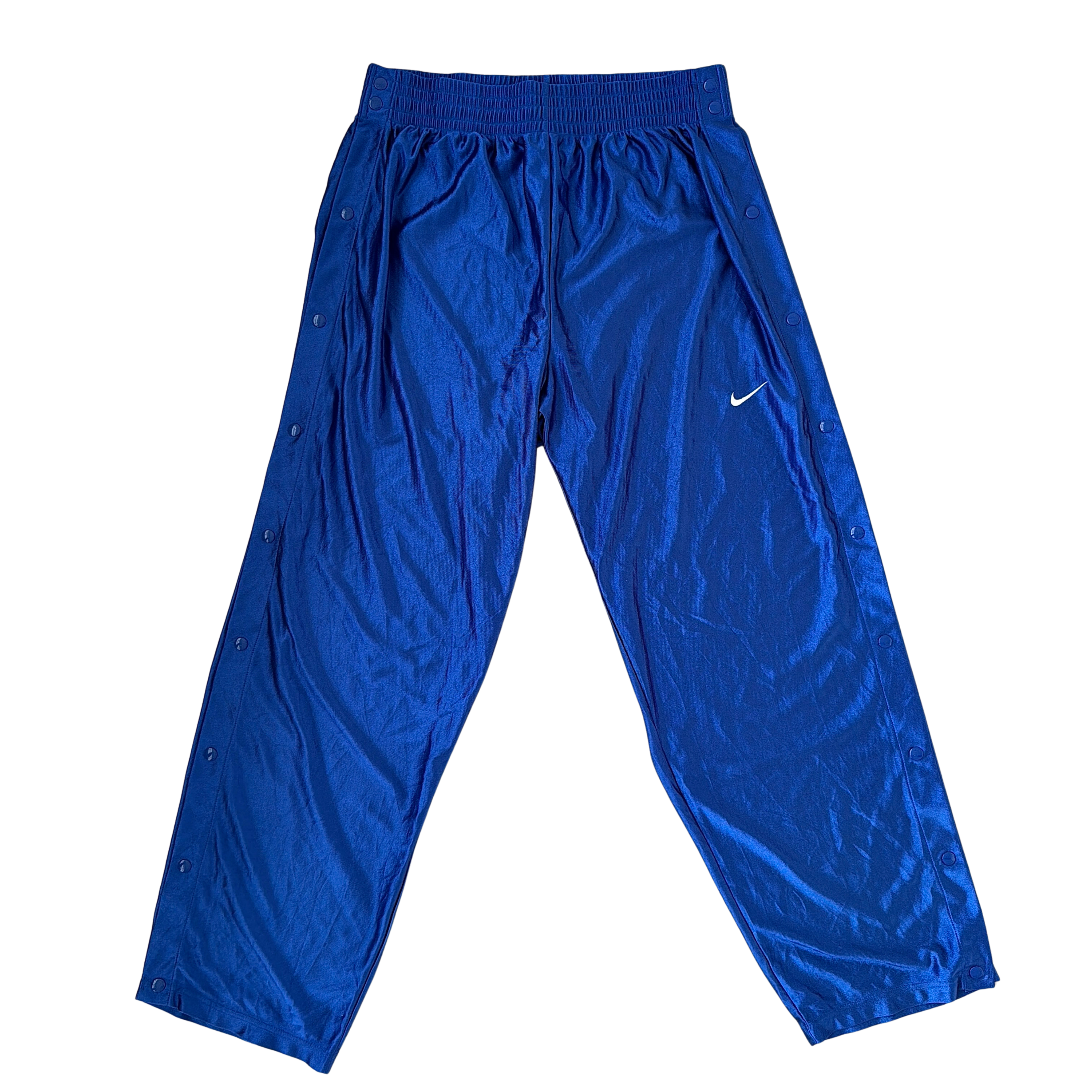Electric blue Nike tear away track pants with snap button sides and white Swoosh logo displayed flat against a black background.