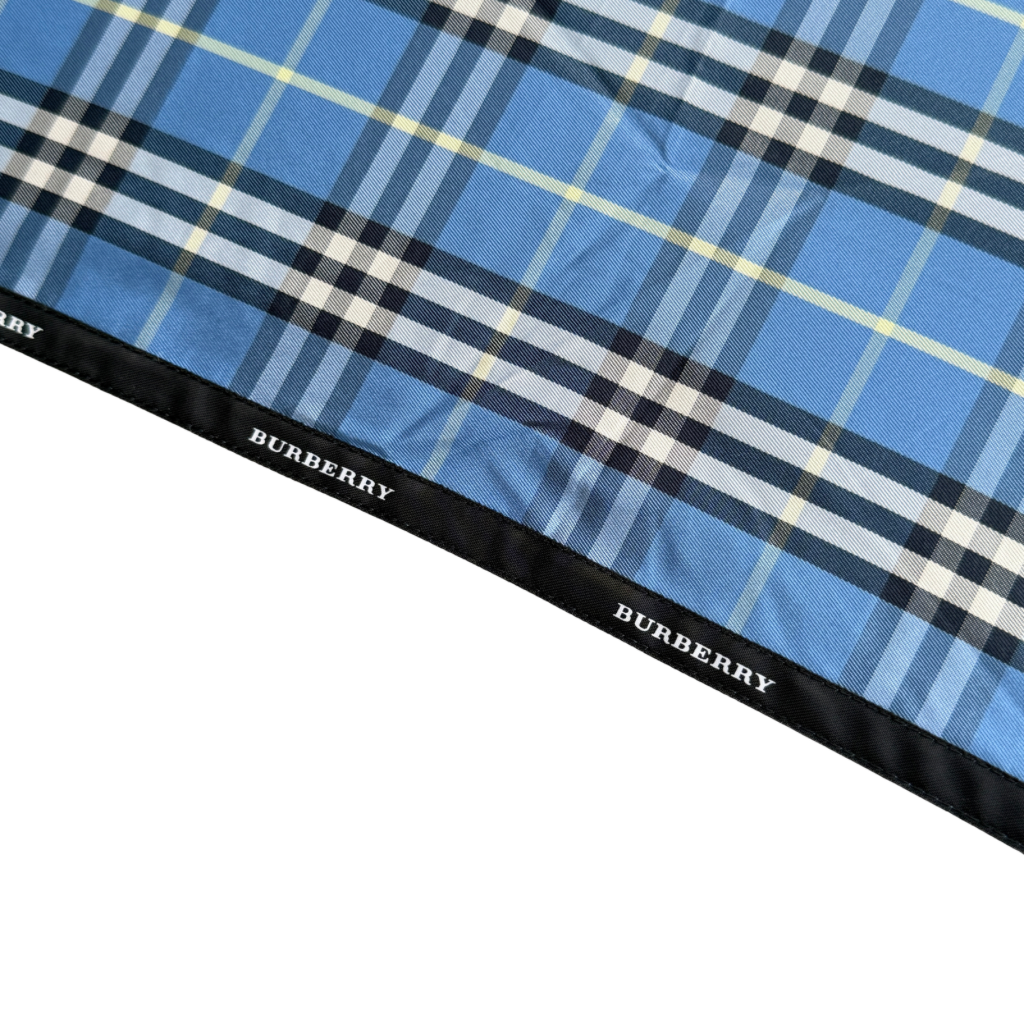 Burberry folding umbrella and matching pouch in blue Nova Check plaid, perfectly folded to showcase its classic pattern and refined finish.