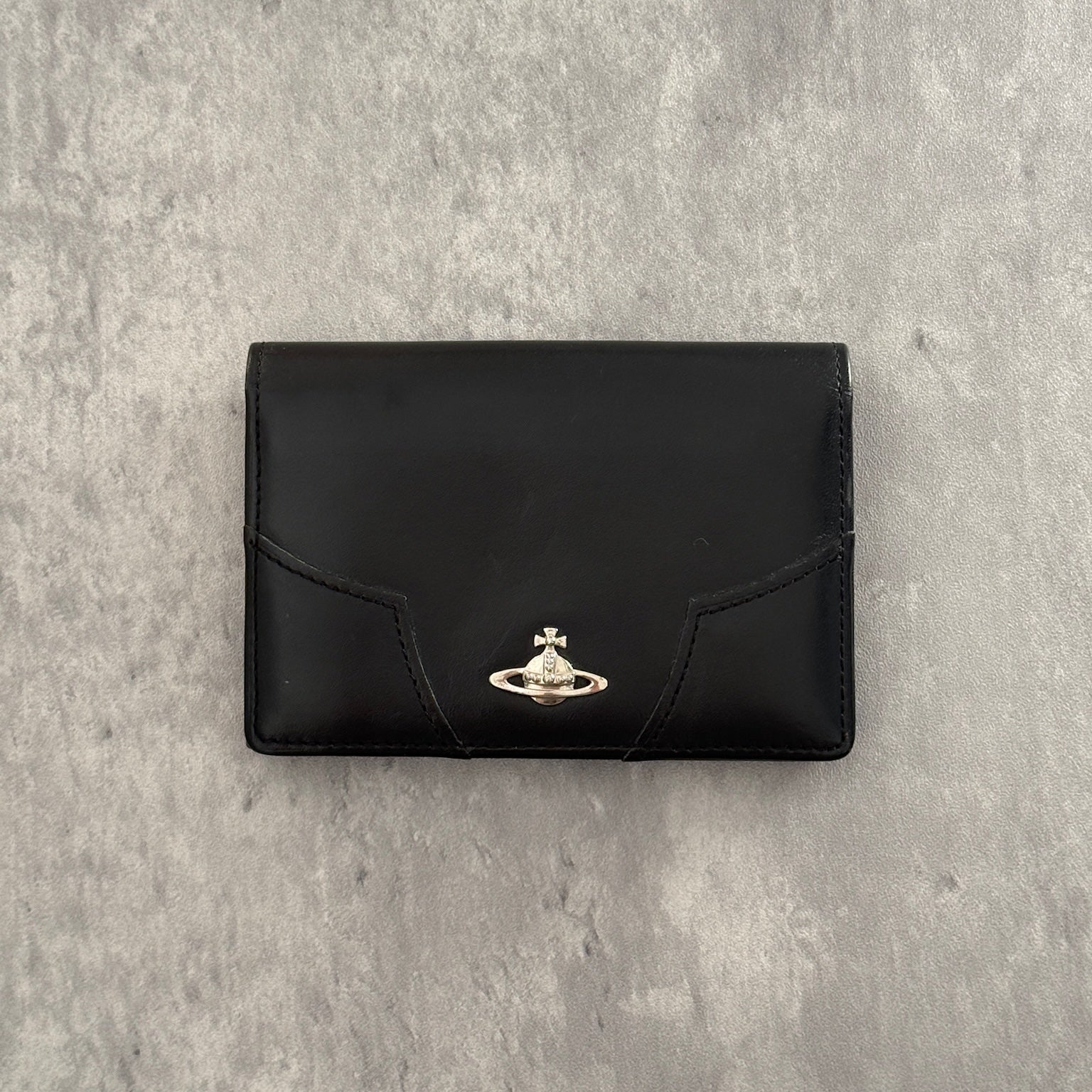 Black Vivienne Westwood cardholder with iconic silver Orb emblem, featuring multiple card slots and a central compartment, perfect for stylish organization.