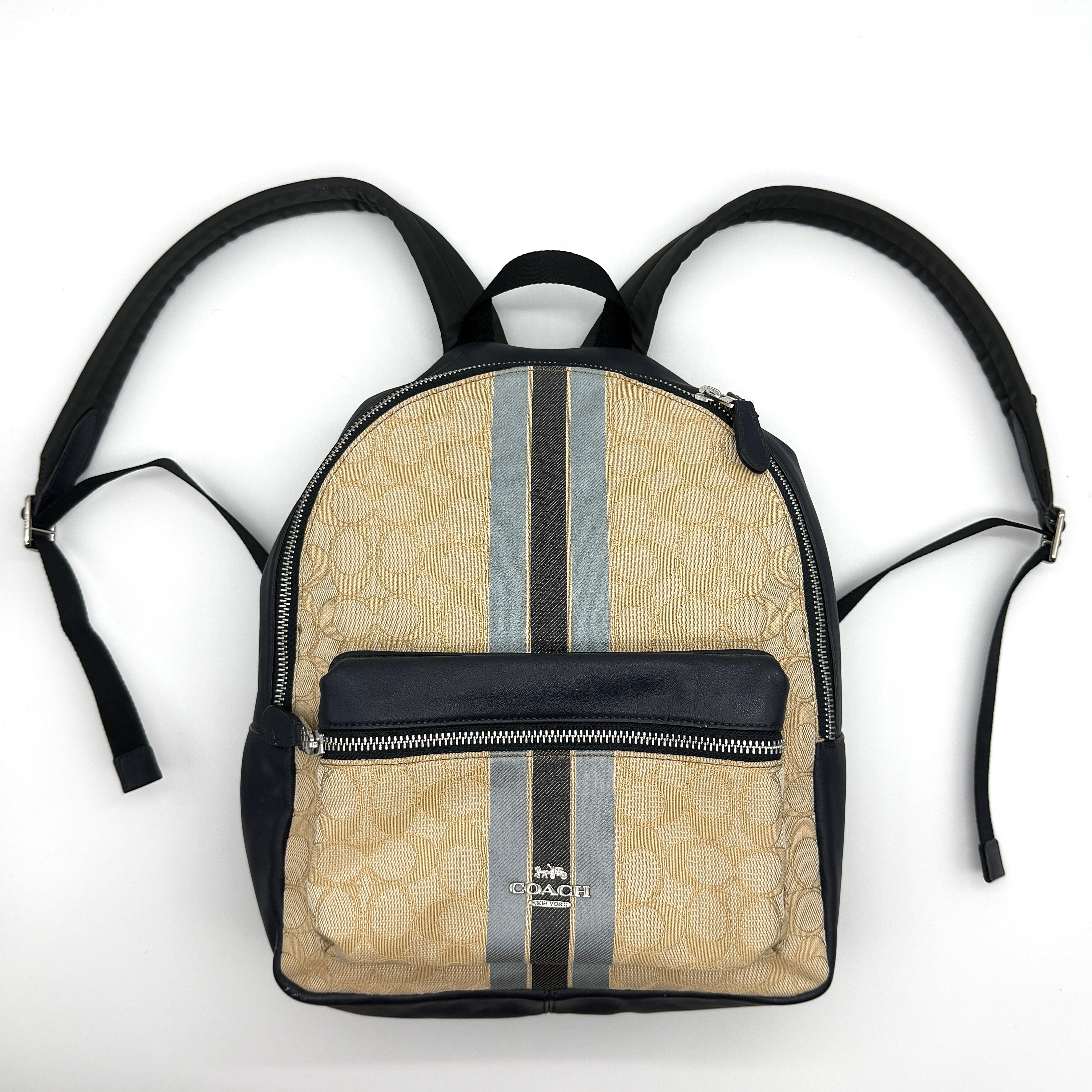Coach Signature Charlie Stripe Backpack in beige monogram canvas with navy leather trim and grey/navy racing stripes.