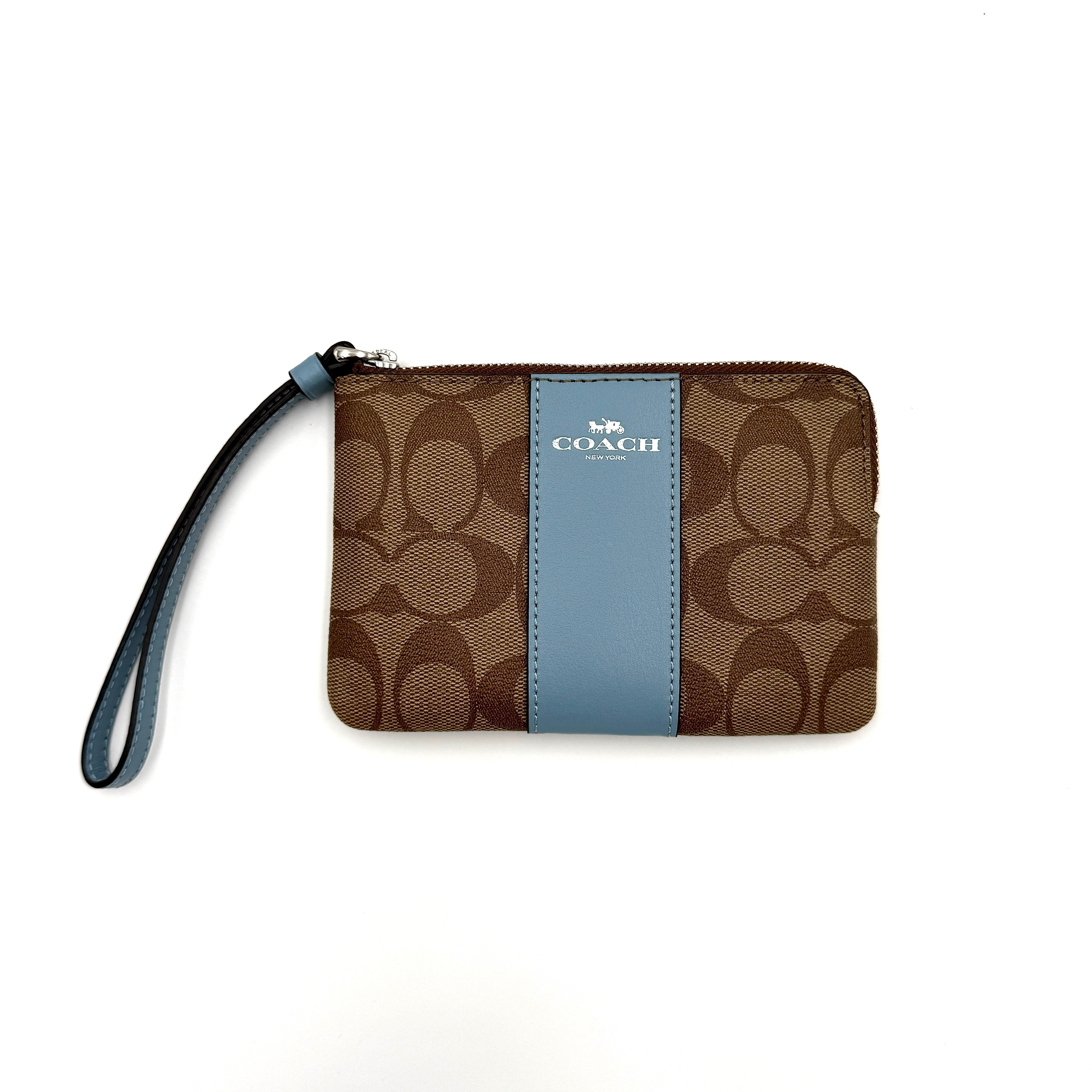 Coach wristlet in light blue and beige, featuring a signature Coach pattern and a practical zip closure with a wrist strap.