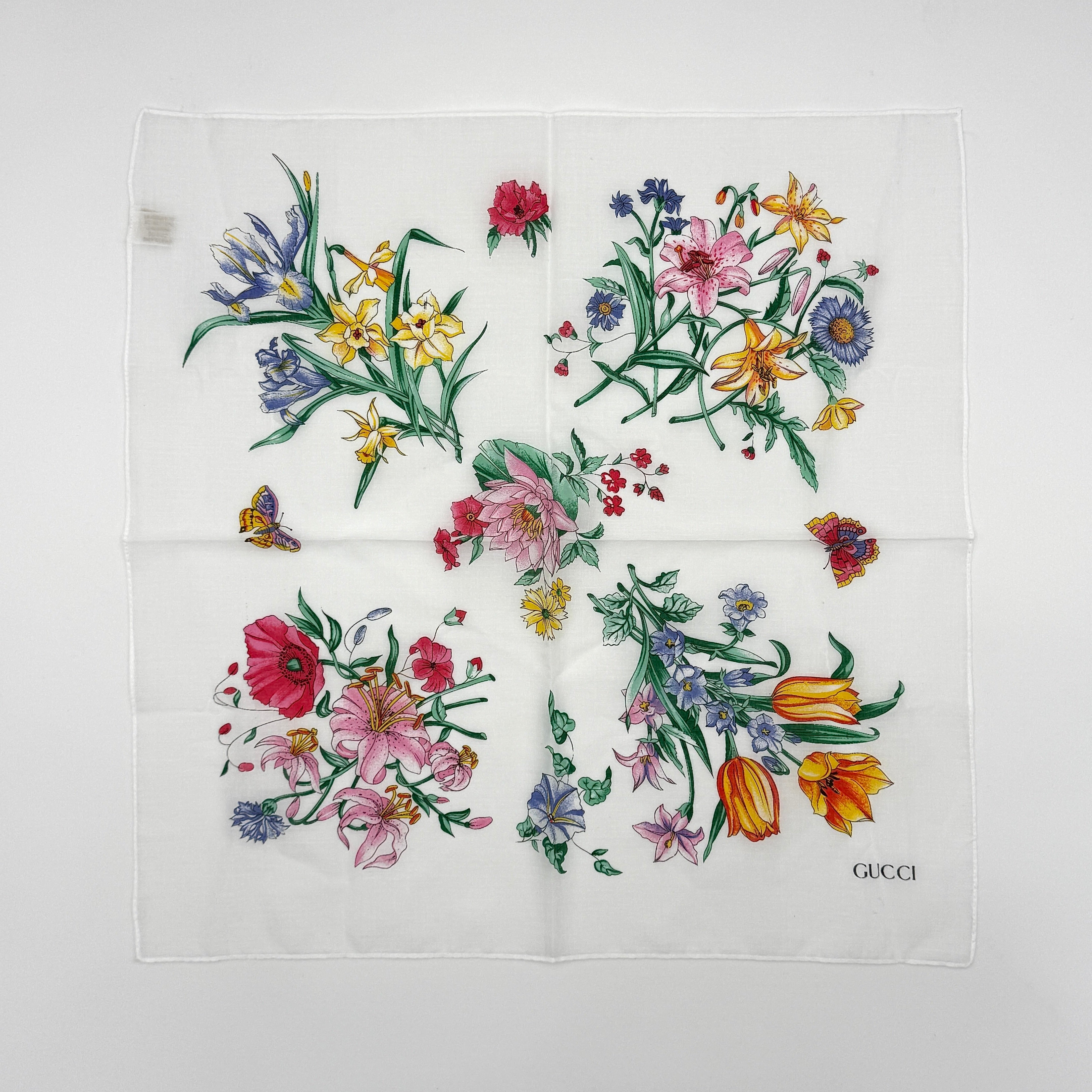 Gucci Flora silk scarf with vibrant multicolor floral pattern on a white background, showcasing intricate botanical designs and Gucci logo detail.