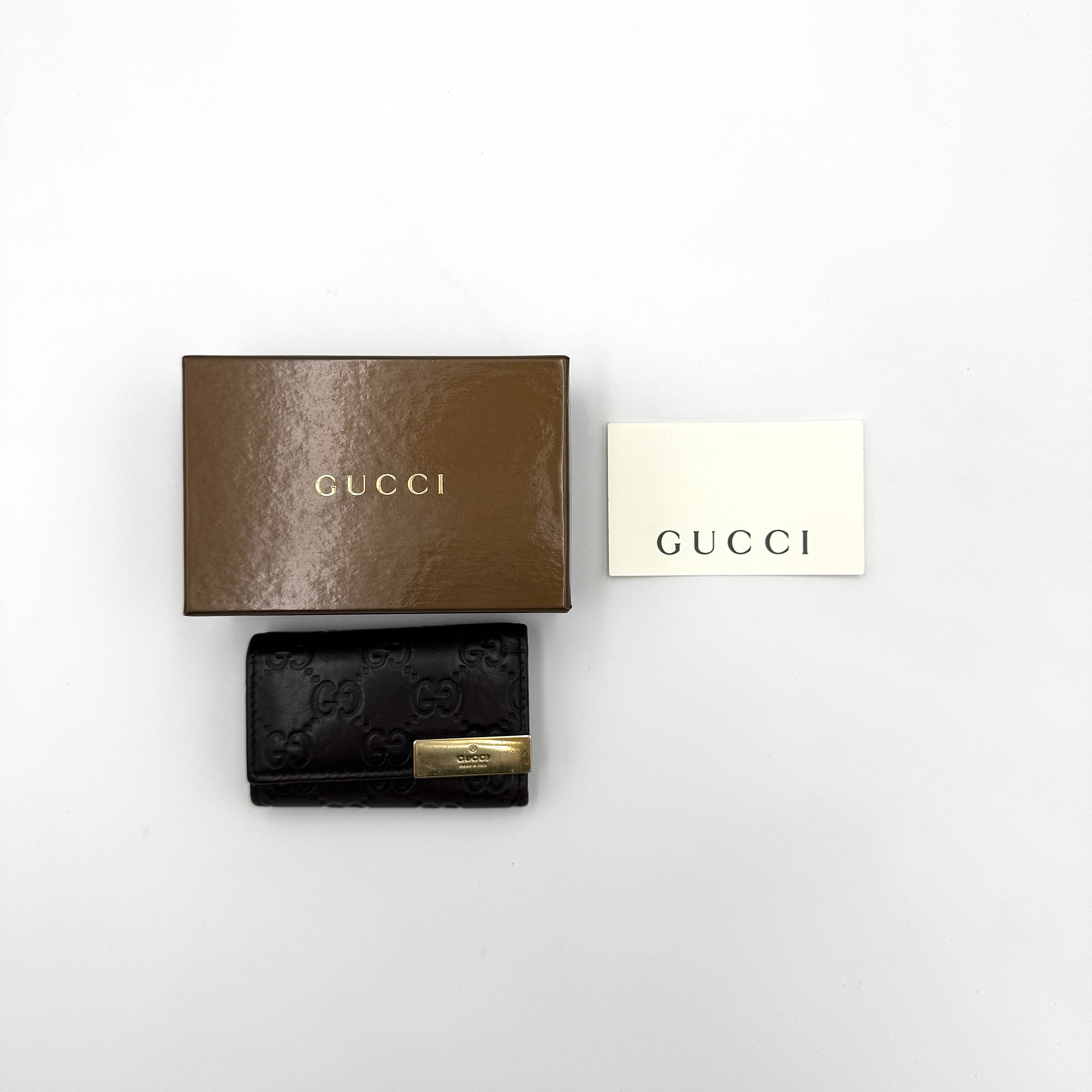 Gucci black GG Guccissima leather key holder with embossed logo pattern and gold-toned plaque.