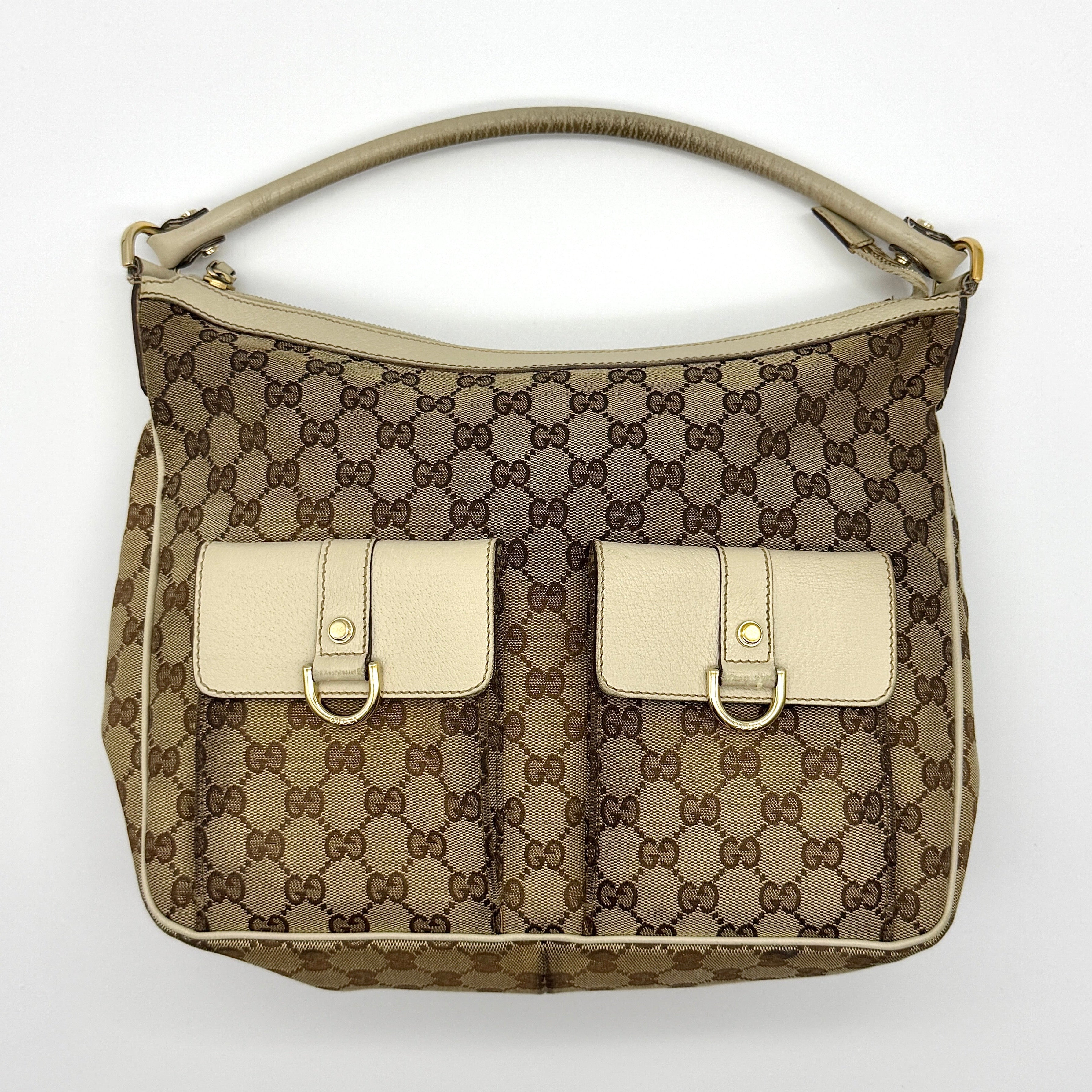 Gucci GG Monogram Hobo Shoulder Bag in beige and white canvas with gold-tone hardware and dual front pockets.