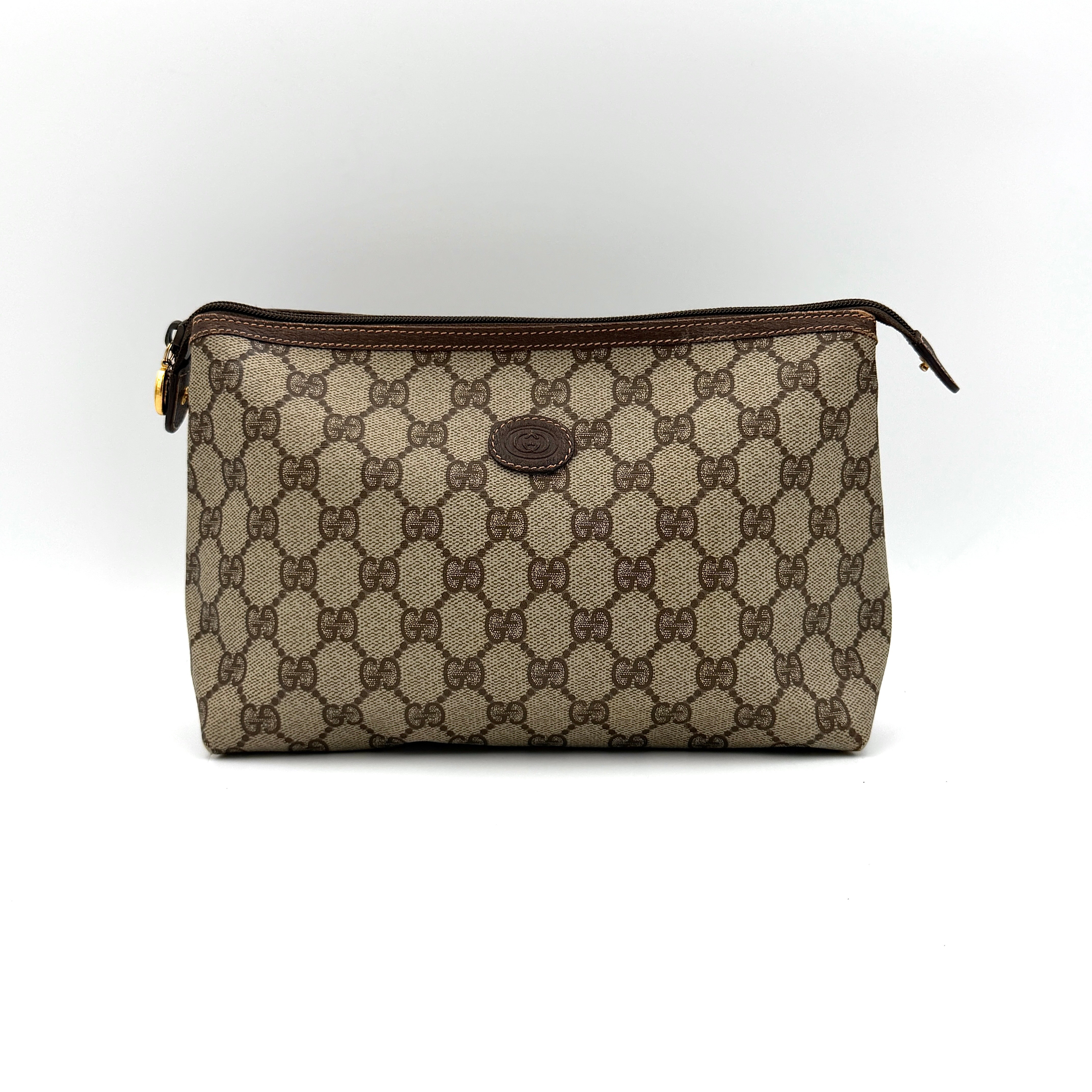 Gucci GG monogram Supreme clutch bag in beige canvas shown from the front with brown leather trim and top zip closure