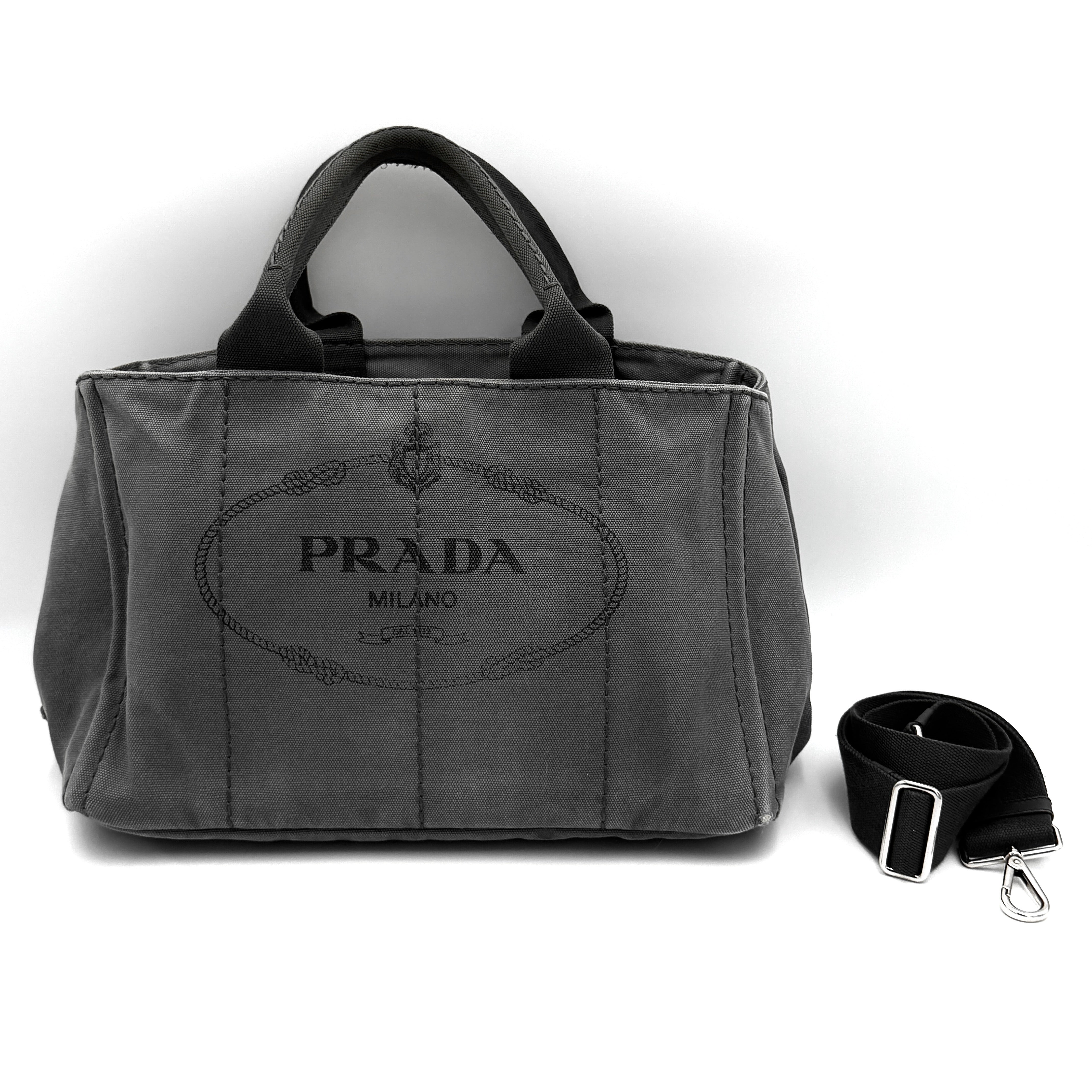 Prada 2-Way Canapa tote bag in grey canvas featuring Prada Milano logo print, dual top handles, and detachable shoulder strap.