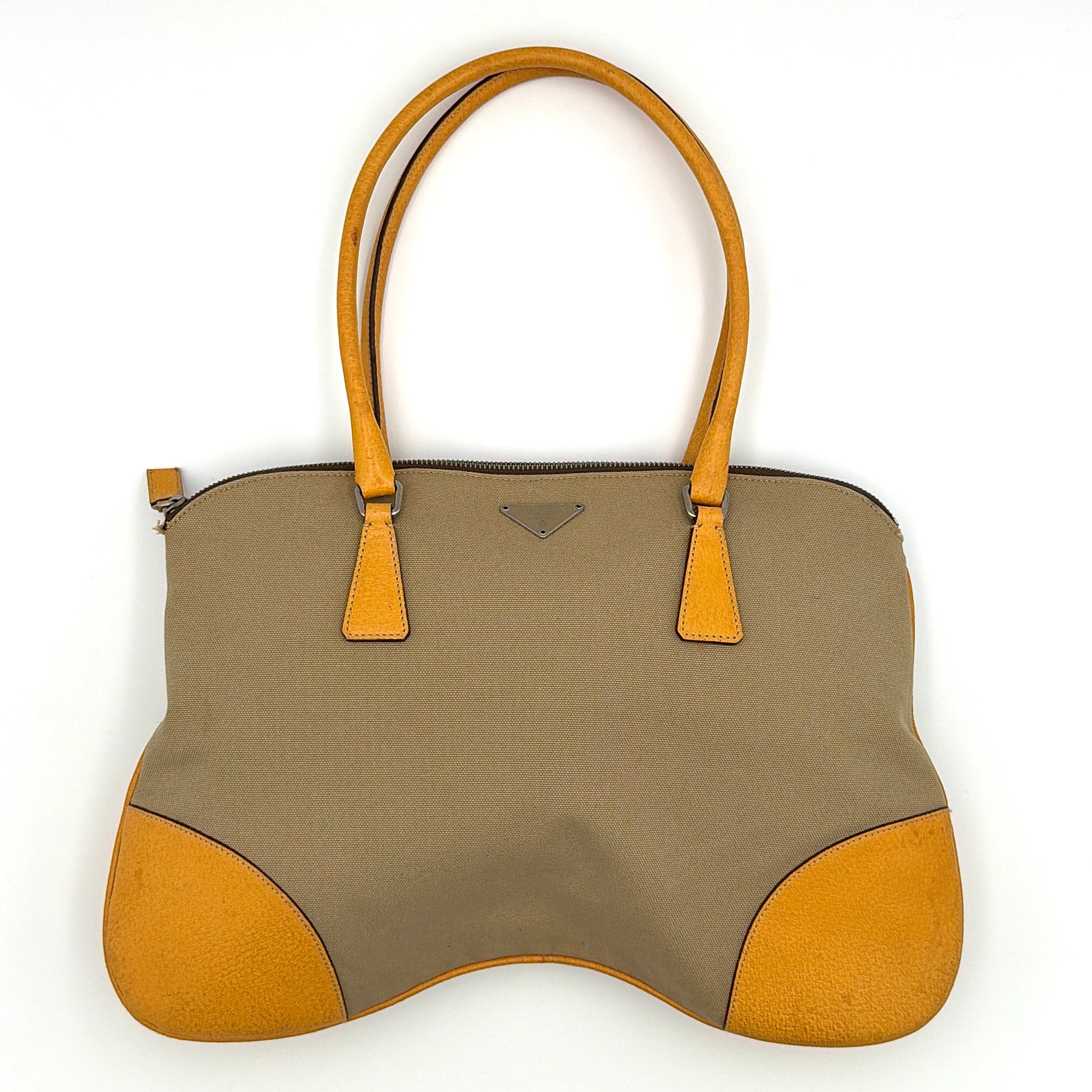 Prada triangle logo canvas shoulder bag in yellow and tan featuring curved silhouette, leather trim corners, and dual shoulder straps