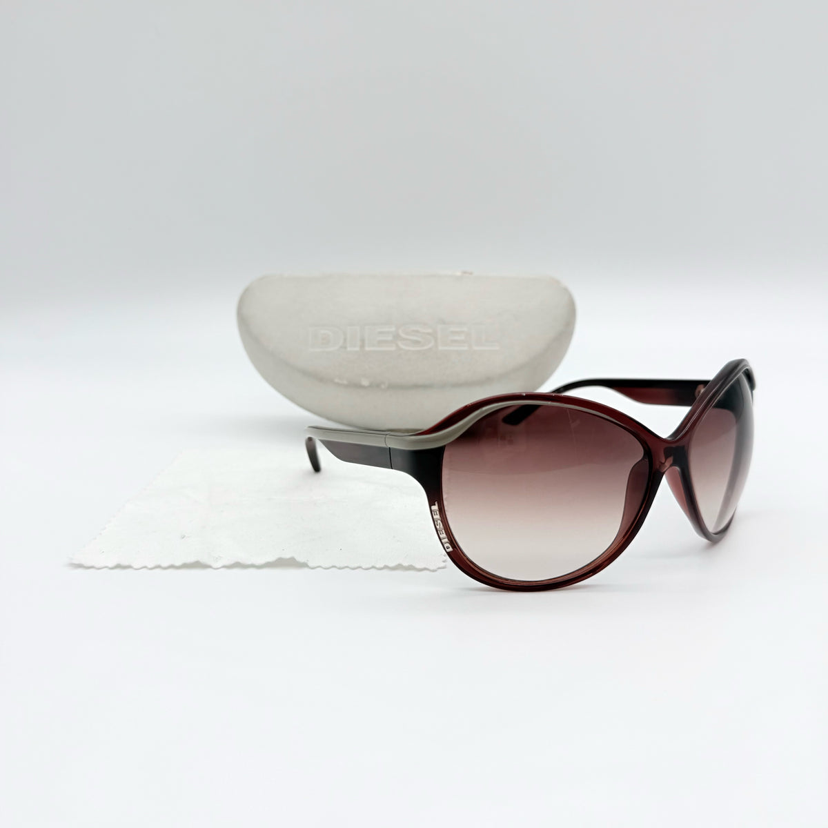 Diesel DS0094 sunglasses in gradient brown with oversized round lenses, shown with branded case and cleaning cloth.