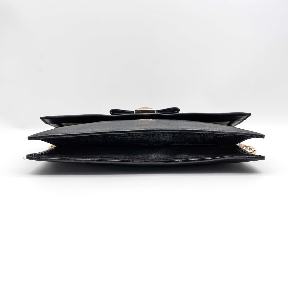 Kate Spade New York black leather shoulder bag with gold chain strap and bow detail, displayed against a white background.