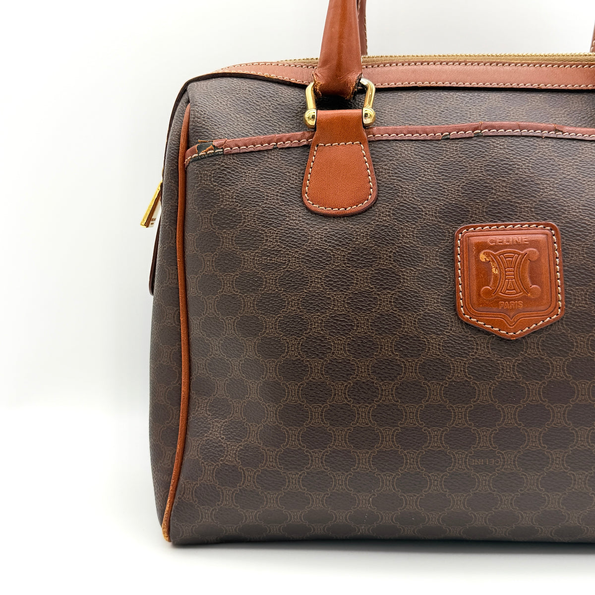 Celine Triomphe Macadam Boston Bag in brown coated canvas with tan leather handles and gold hardware on a white background.