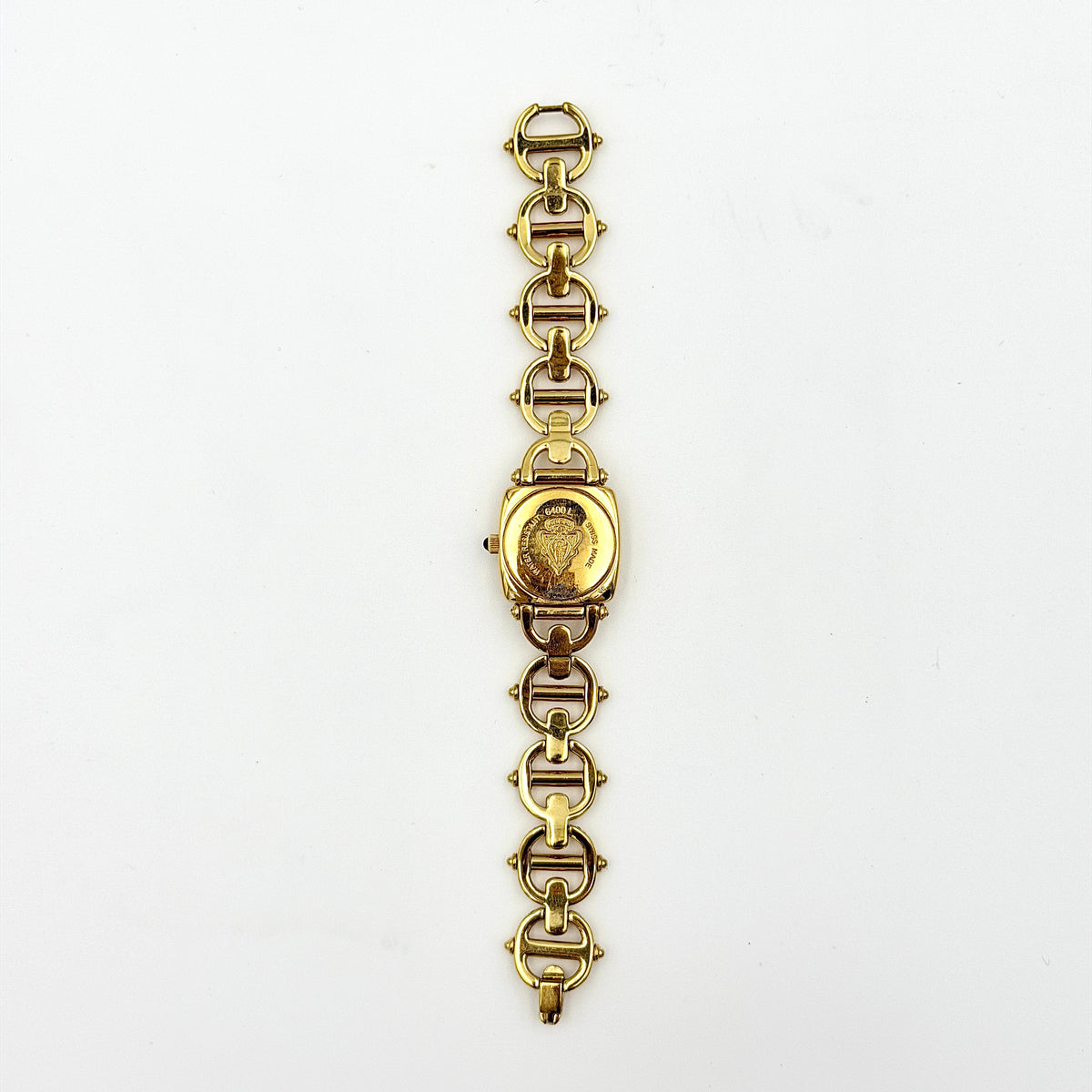 Gucci 6400L gold-tone bracelet watch with a black dial and distinctive horsebit links, showcased on a clear stand.