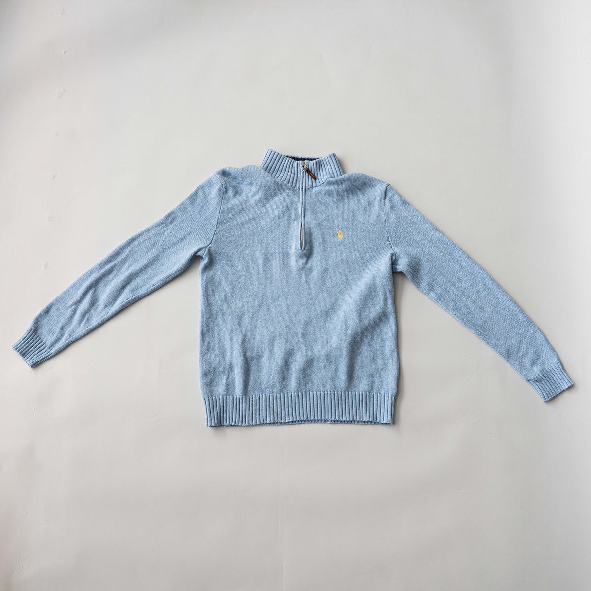 Polo Ralph Lauren light blue quarter zip mockneck cotton sweater laid flat with visible yellow pony logo.