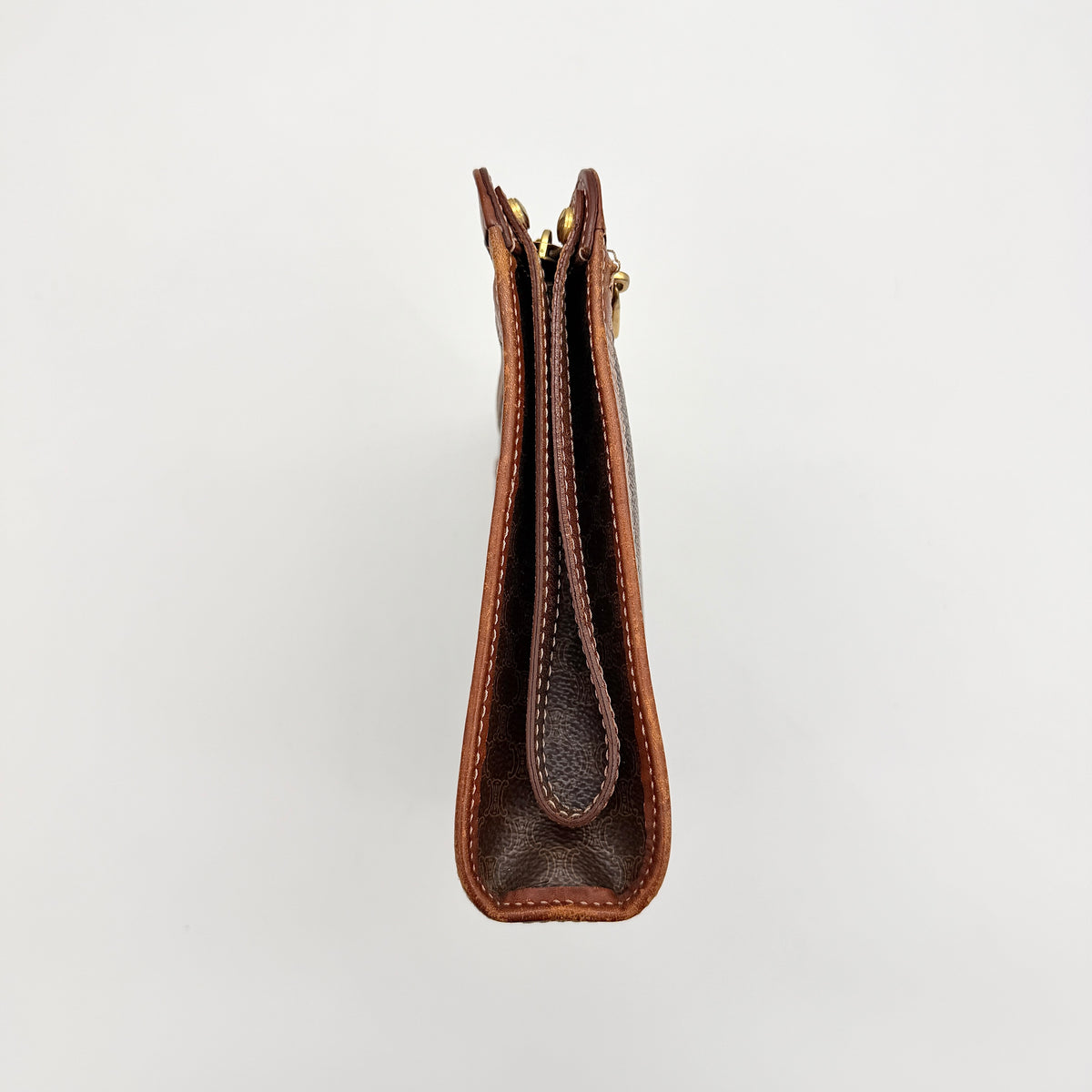 Celine Triomphe Macadam clutch bag in brown canvas with tan leather trim and gold hardware, shown with wrist strap.