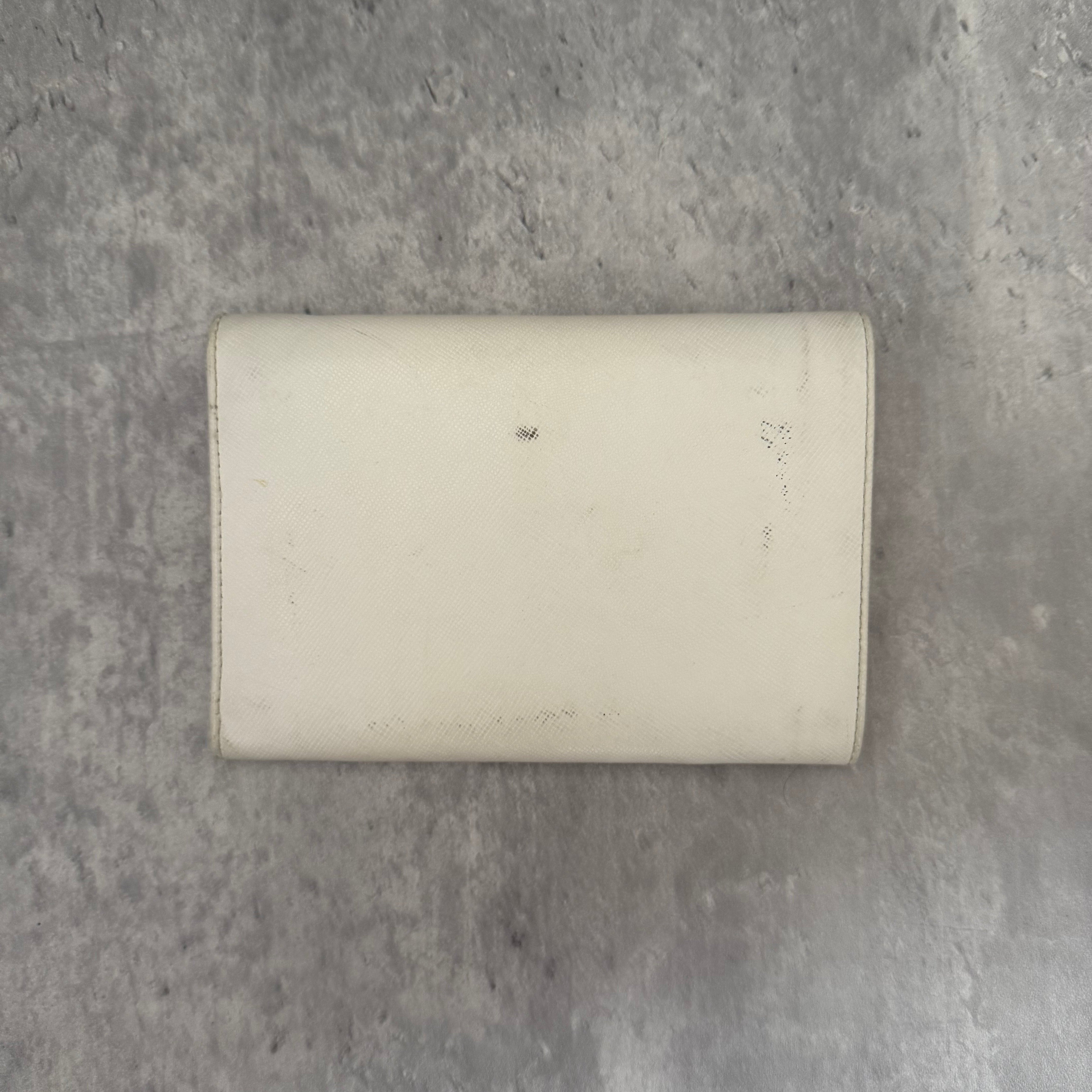 Pre-loved Prada Tessuto Nero leather trifold wallet with triangle logo plate in off-white, featuring card slots and a snap closure.