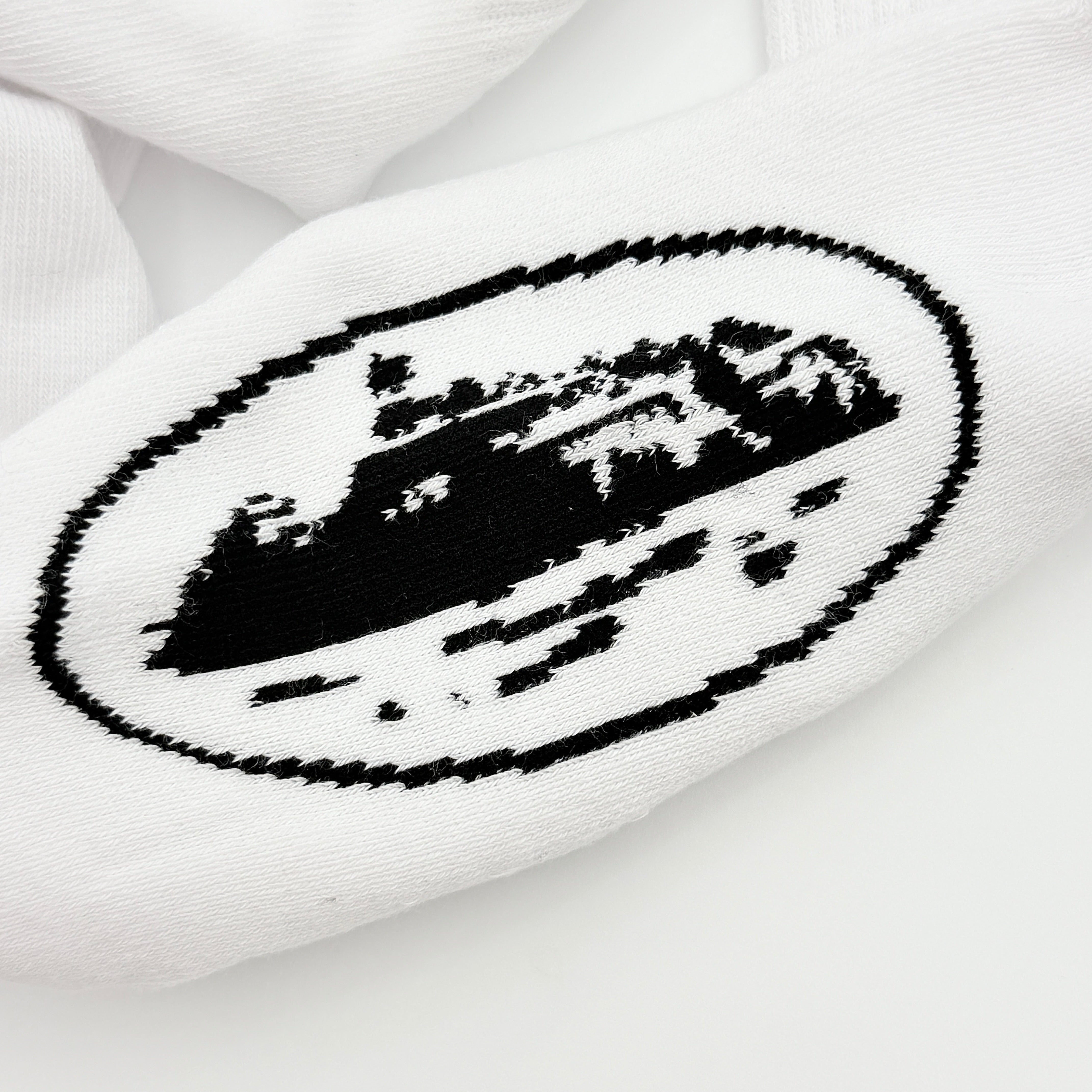 A pair of Corteiz Alcatraz white socks with black logo on the ankle and statement text on the sole.