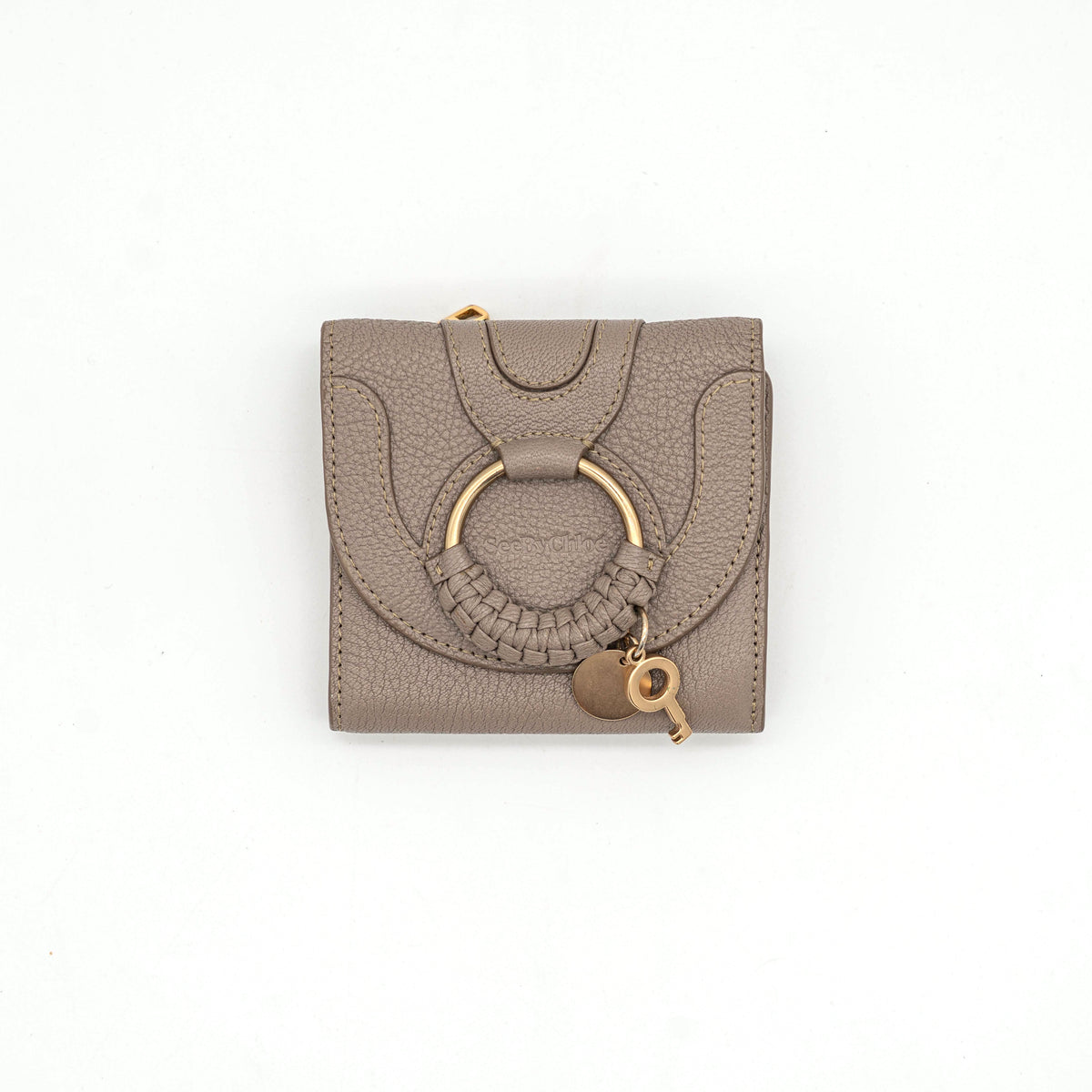 See by Chloe Hana tri-fold wallet in grey grained leather with gold-tone ring and charms, photographed closed on a white background.
