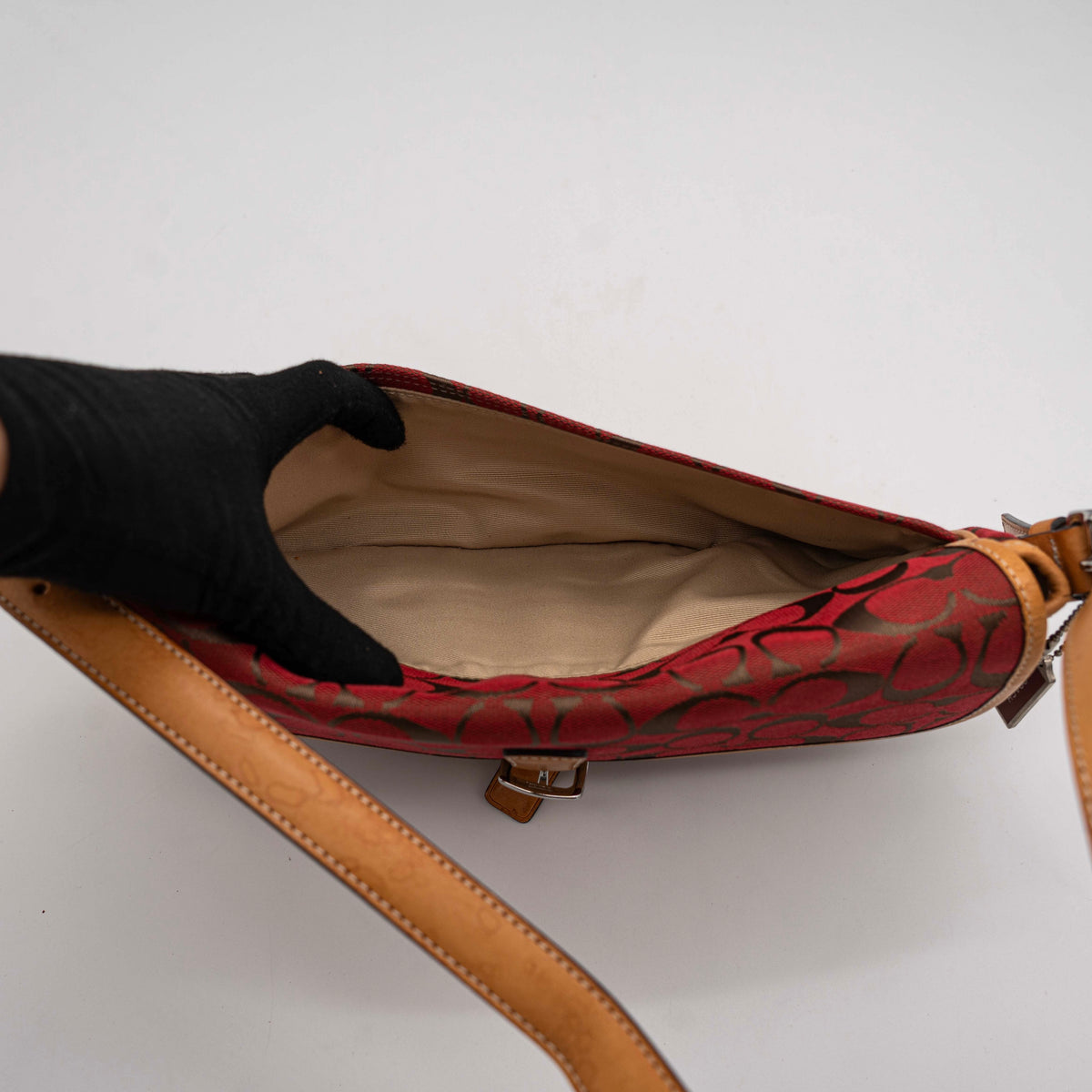 Coach Signature Soho Buckle Baguette in red and tan canvas with leather trim and a silver buckle, shown on a white background.