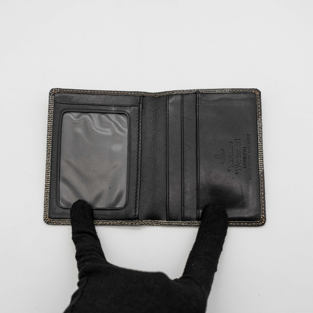 Vivienne Westwood black and grey stripe cardholder with gold Orb plaque against a white background.