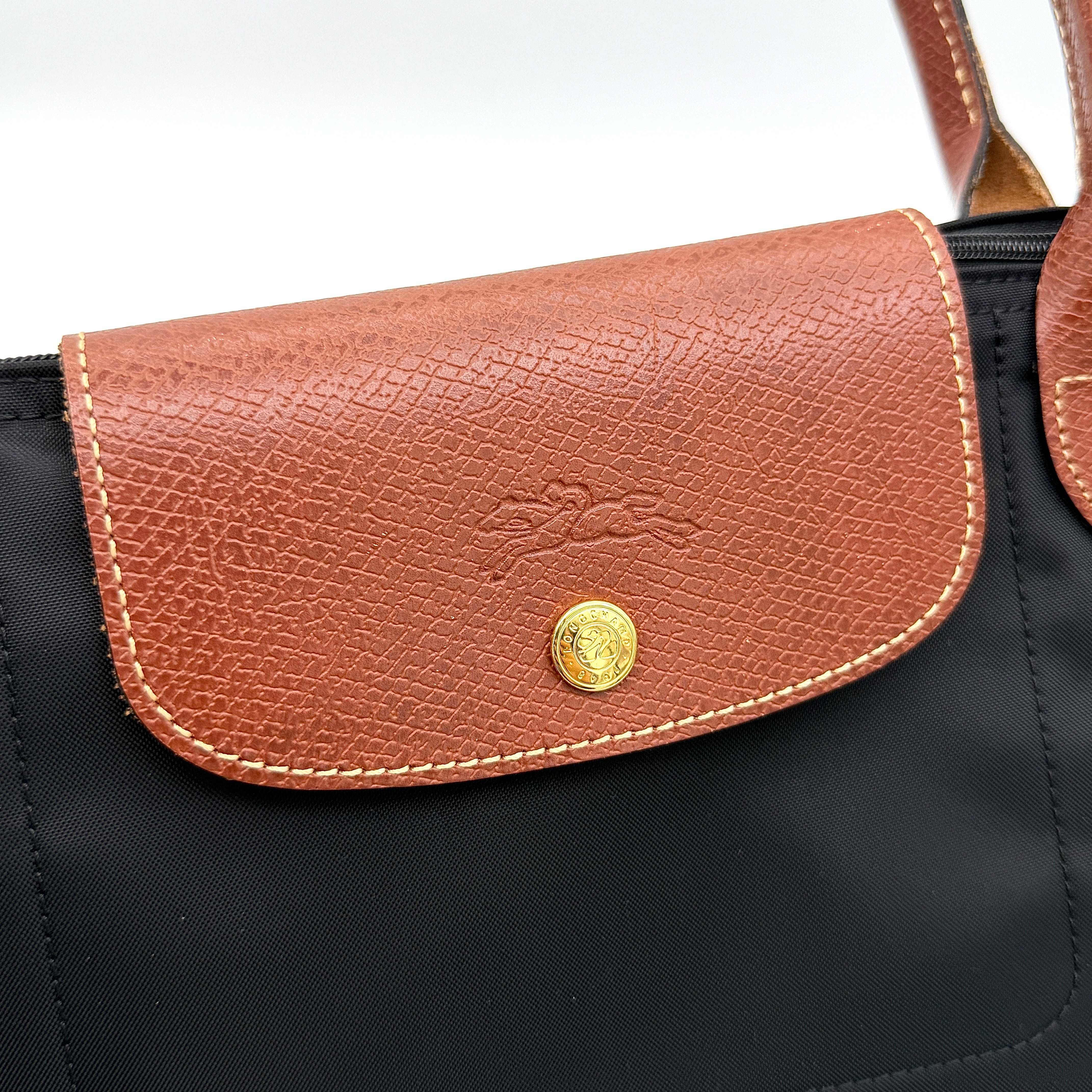 Longchamp Le Pliage Original Tote Bag in black with brown leather handles and flap, photographed against a white background.