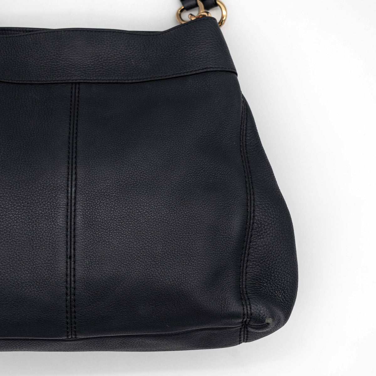 Coach Lexy Shoulder Bag in black pebbled leather with gold-tone hardware and double handles, styled against a white background.