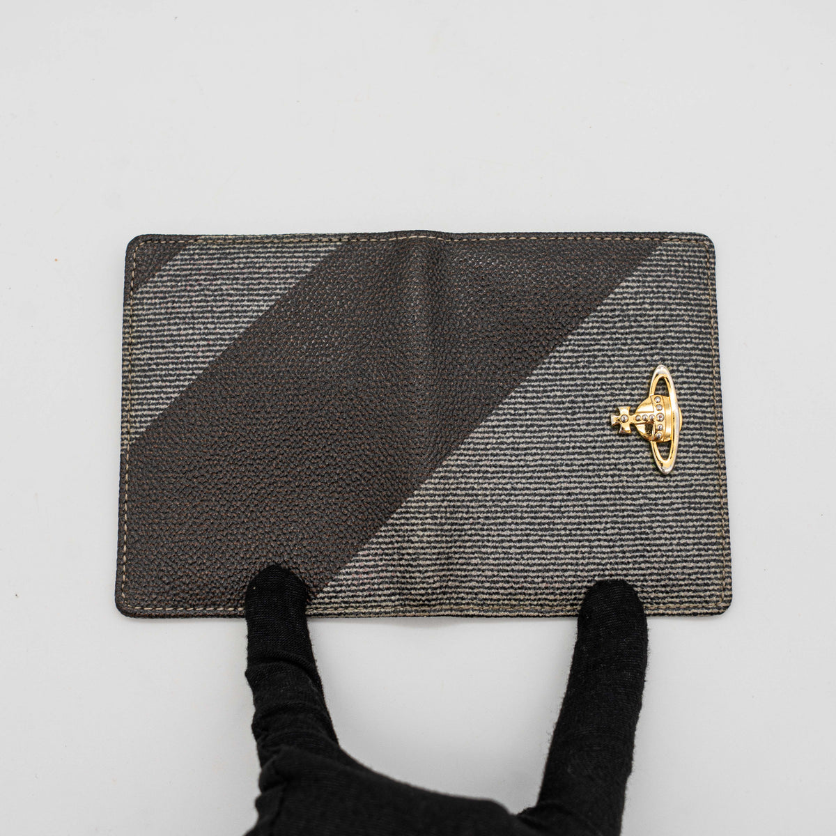 Vivienne Westwood black and grey stripe cardholder with gold Orb plaque against a white background.