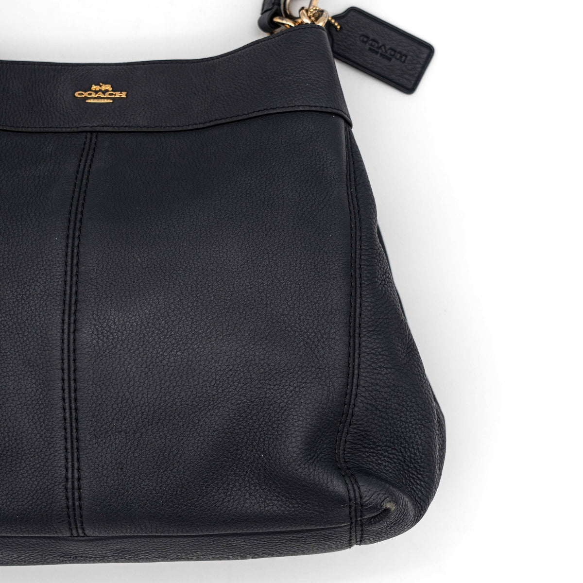 Coach Lexy Shoulder Bag in black pebbled leather with gold-tone hardware and double handles, styled against a white background.