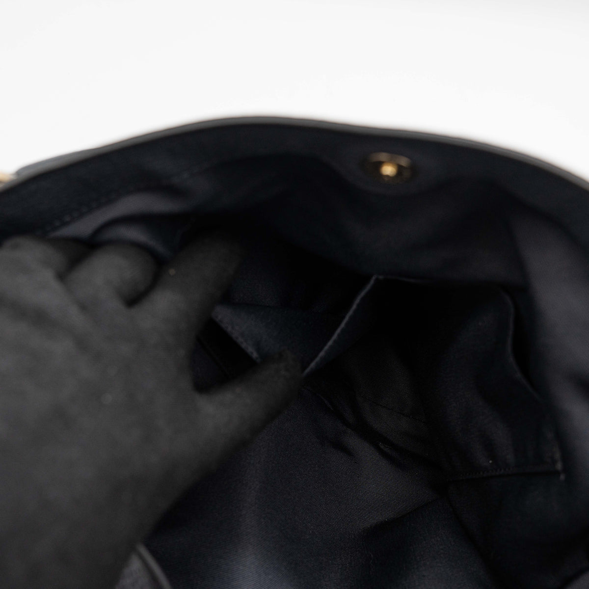Coach Lexy Shoulder Bag in black pebbled leather with gold-tone hardware and double handles, styled against a white background.